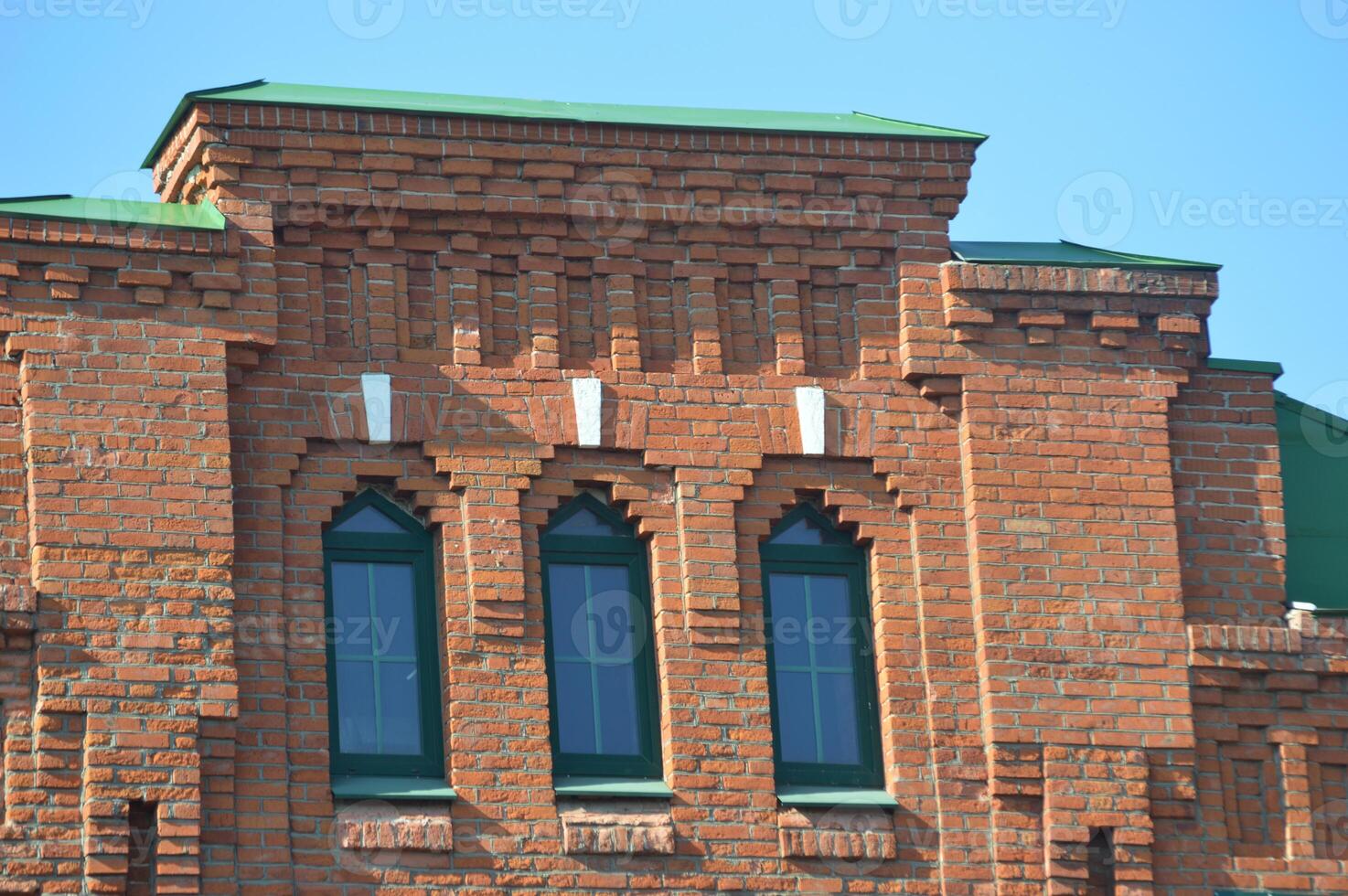 Part of an old red brick house. Restored facade with windows and stepped roof. photo