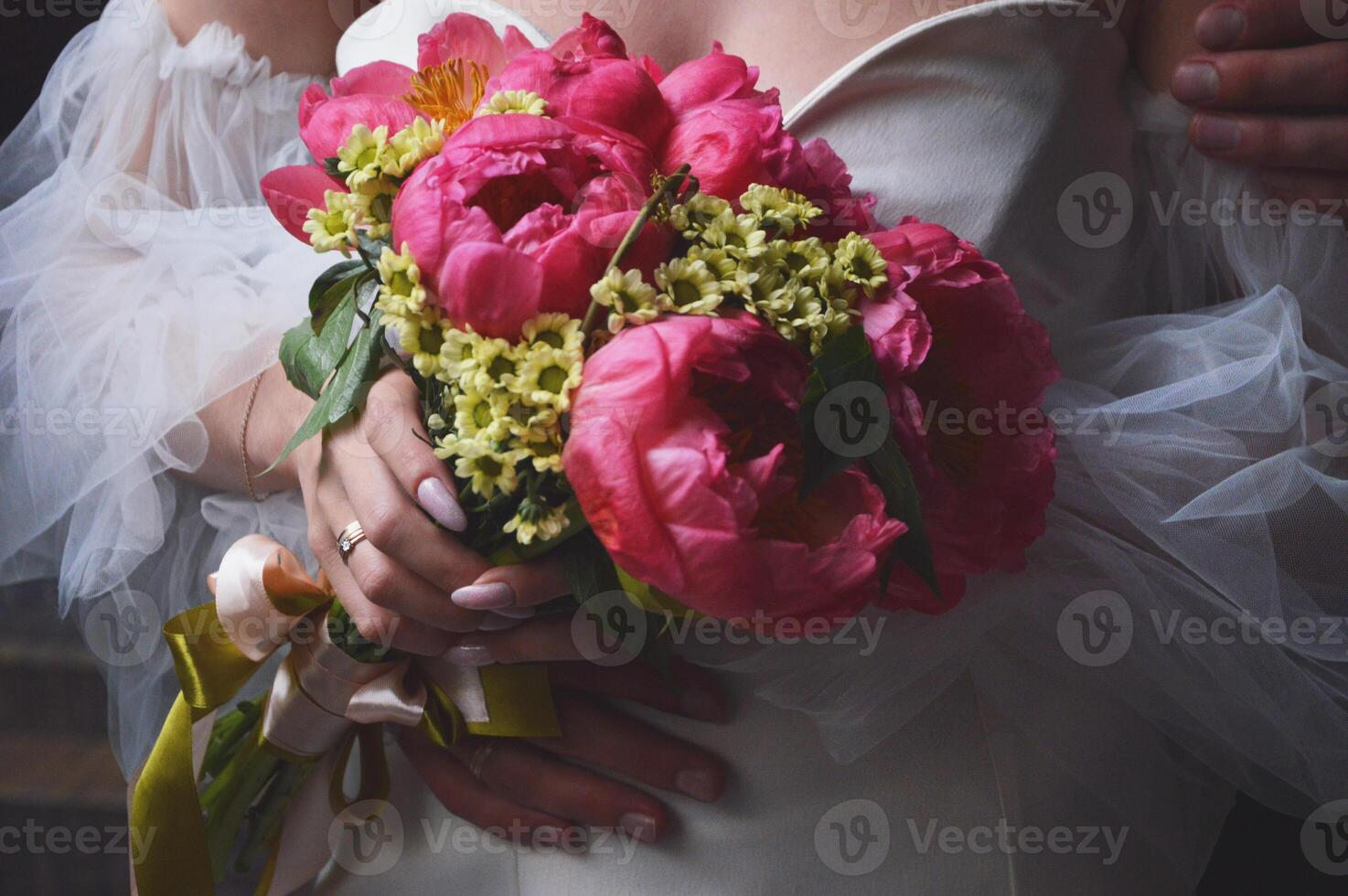 un novia en un blanco vestir con hinchado mangas sostiene un Boda ramo de flores de brillante rosado peonías en su manos. foto