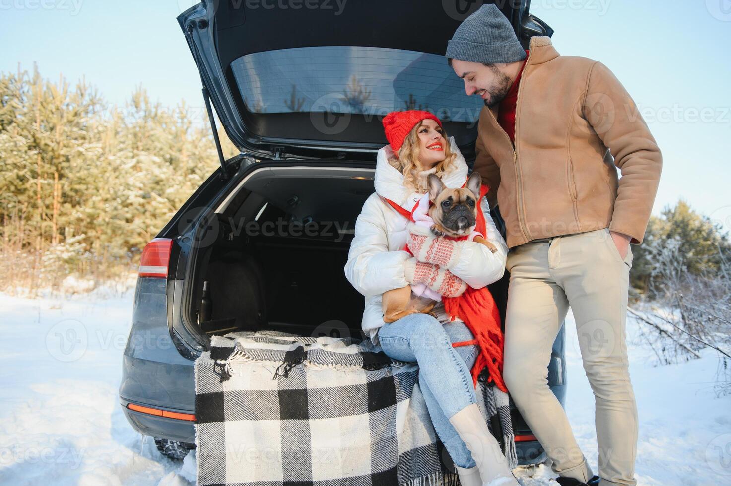 Happy couple sitting in open car back, having stop off. Romantic traveling concept. Winter forest. photo