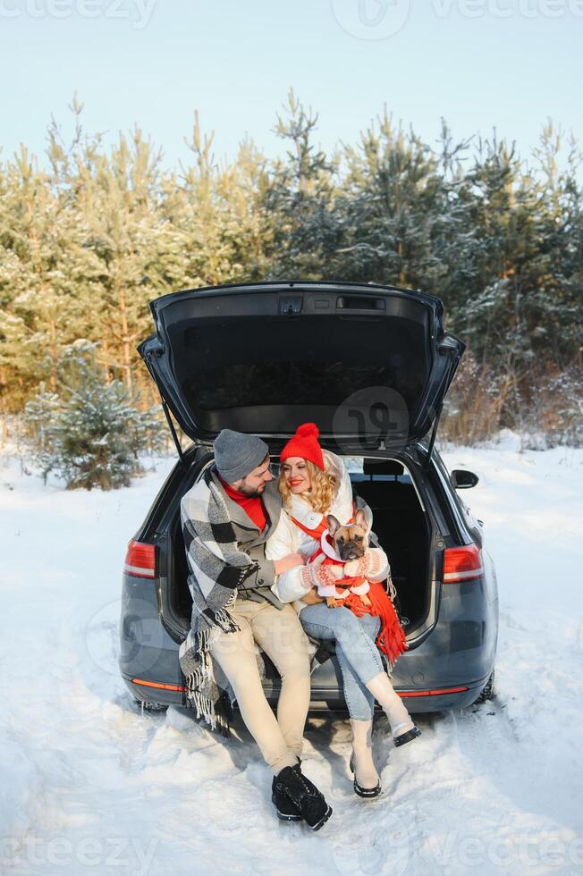 Happy couple sitting in open car back, having stop off. Romantic traveling concept. Winter forest. photo