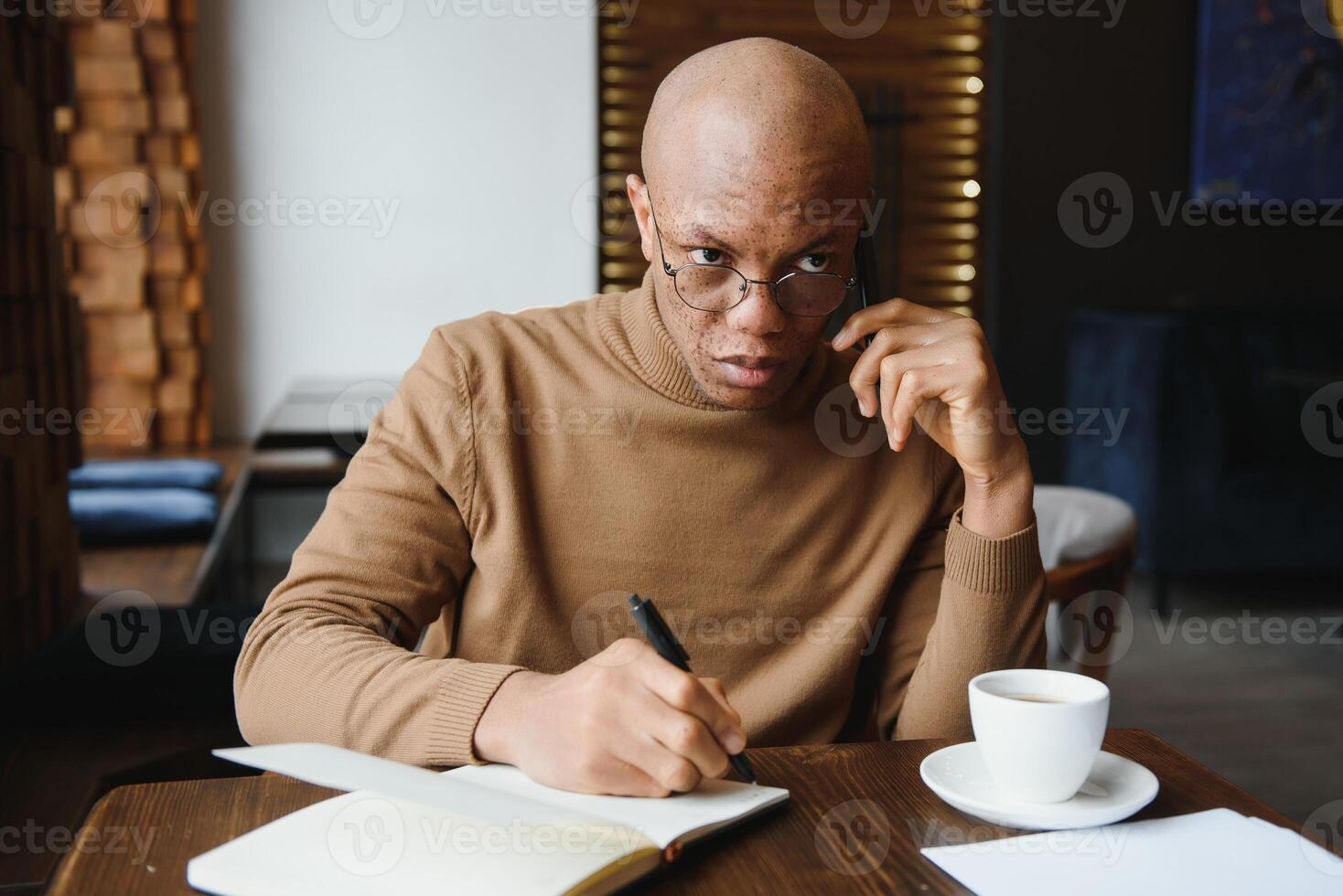 African-Ameican entrepreneur wearing shirt with rolled up sleeves looking through window with thoughtful and serious face expression, feeling nervous before meeting with business partners at cafe. photo