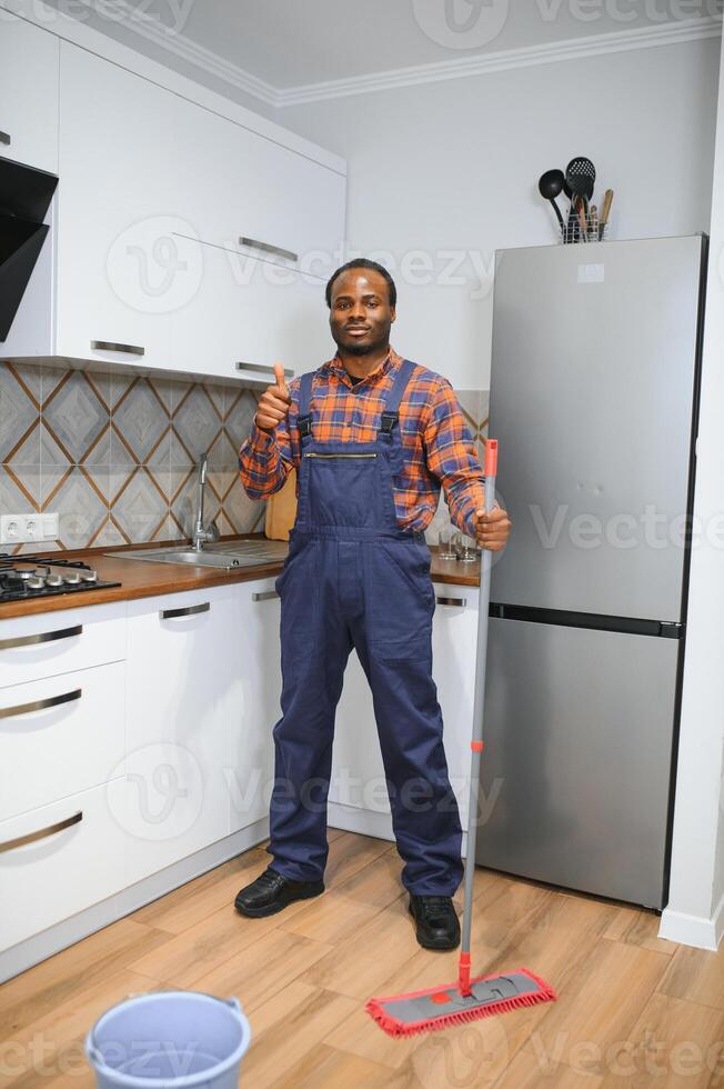 Young african man washes the floor with a mop in the room photo