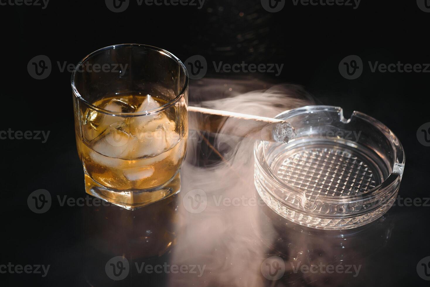 Whiskey drink with smoking cigar photo