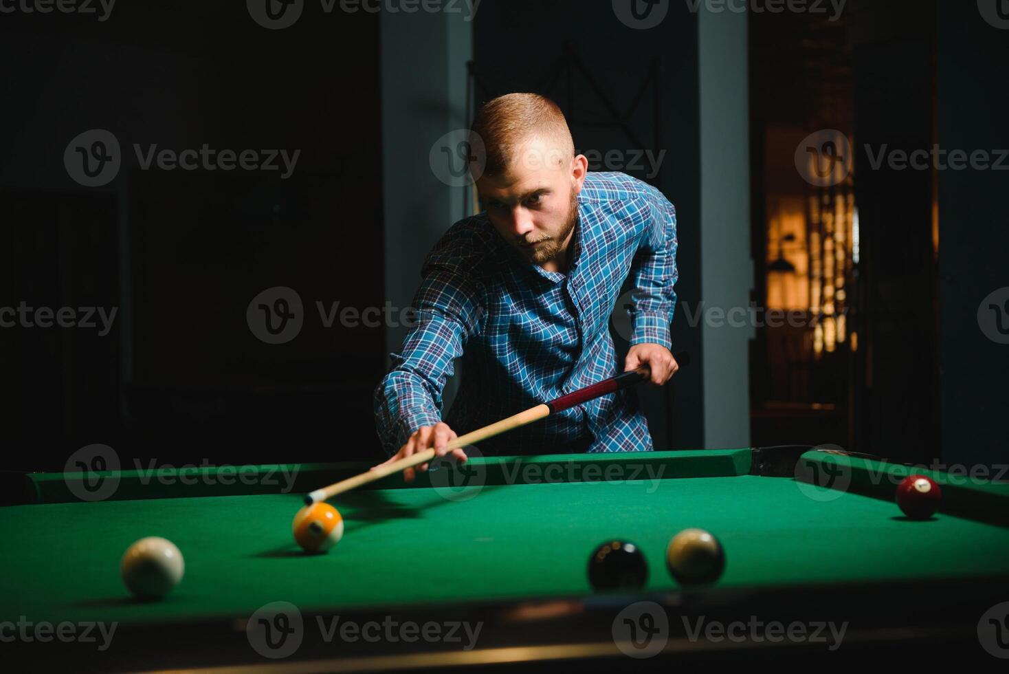 joven hermoso hombre propensión terminado el mesa mientras jugando snooker foto