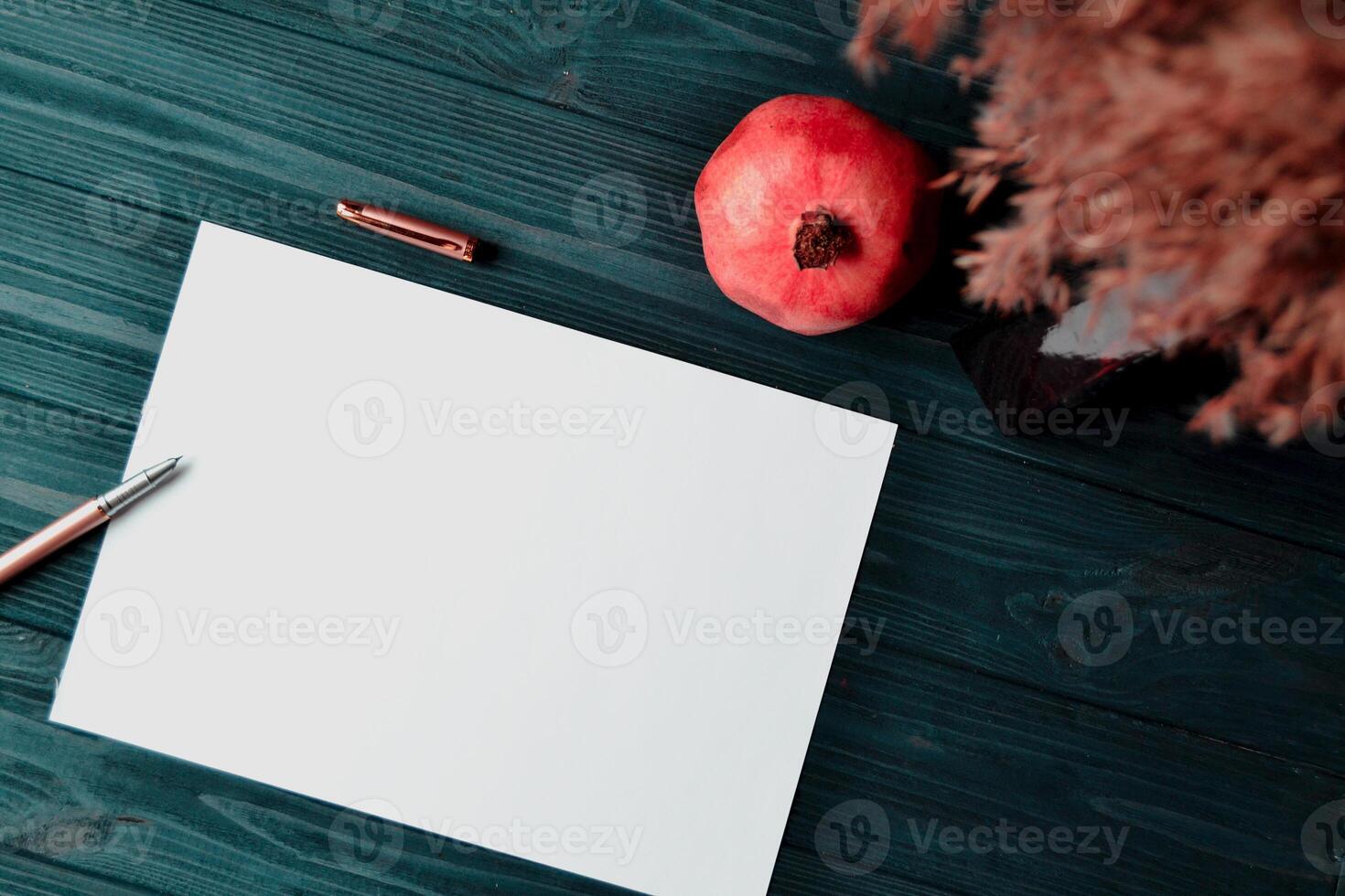 el sábana de blanco papel con bolígrafo y granate en el oscuro azul de madera escritorio. Clásico antecedentes con sitio para texto. foto