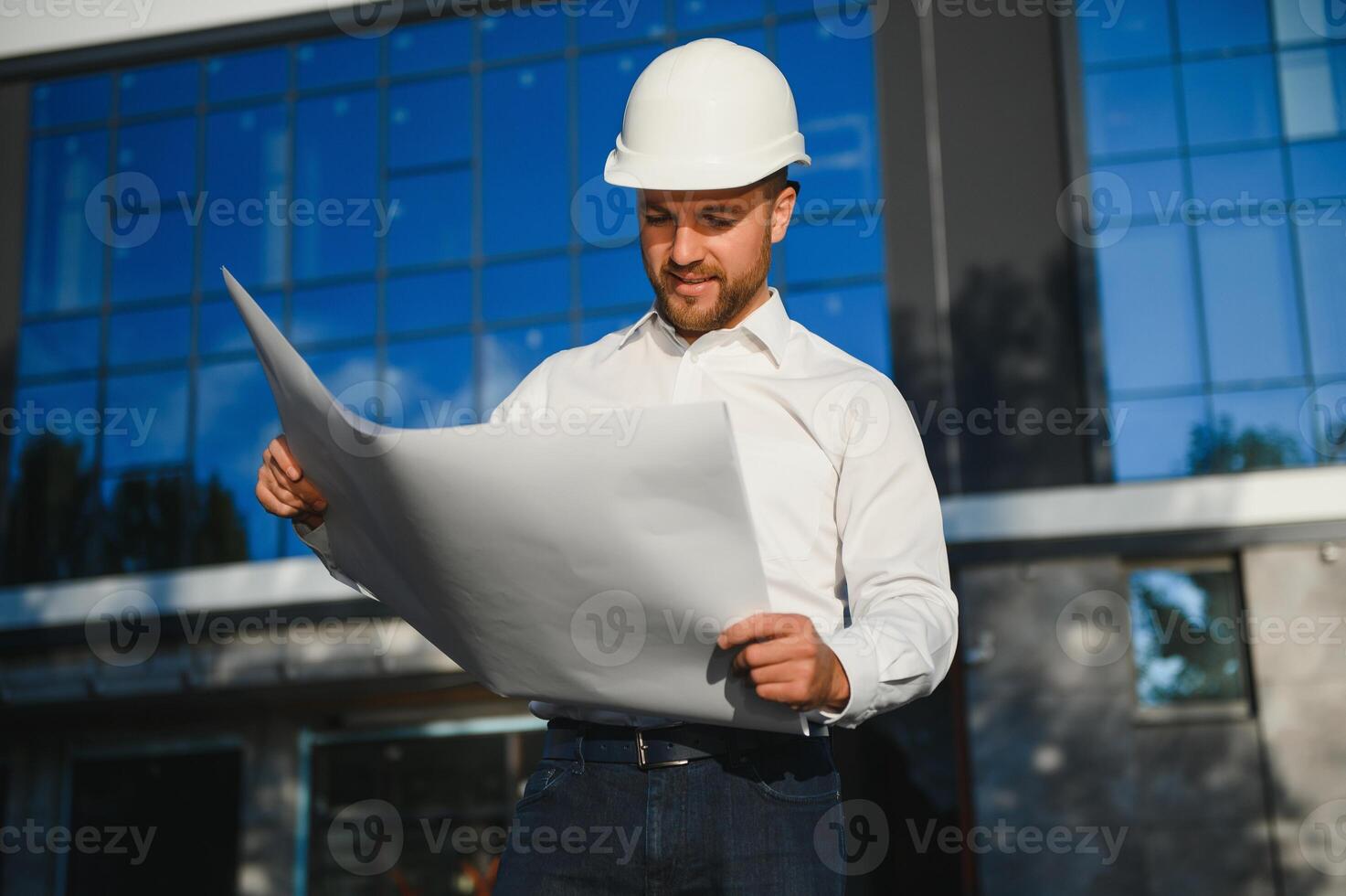 Engineer next to building cranes. Concept - large construction project. Architect directs the construction process. Drawings and tablet in the hands. photo