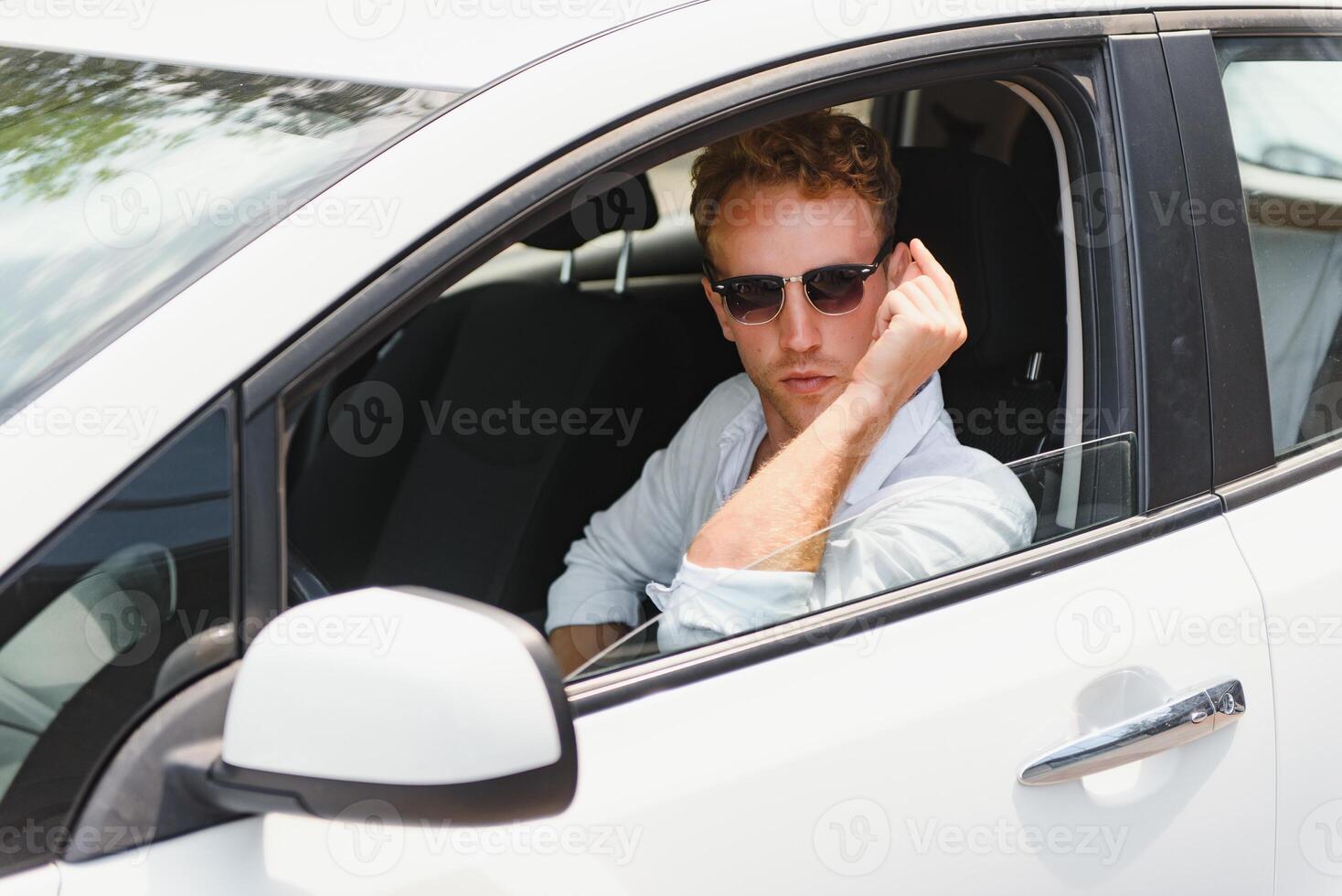 Test driving of new generation electro vehicle with self driving system. Handsome Caucasian man sitting behind the wheel of new modern car and smiling at camera. photo