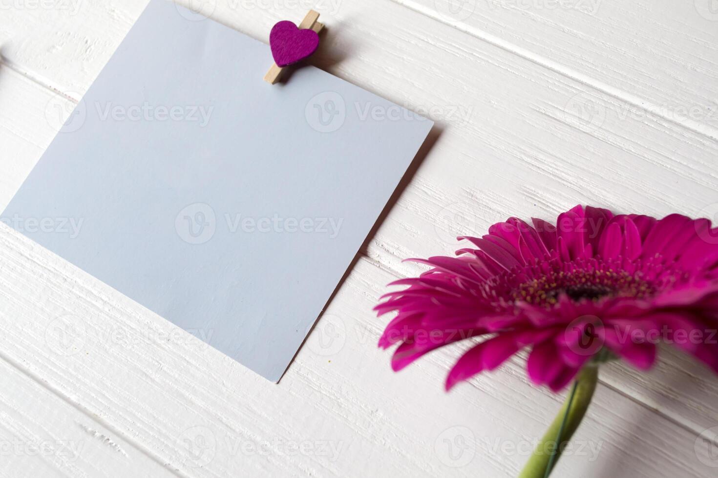 Blue memo sheet, pen and gerbera on a white wooden desk. photo