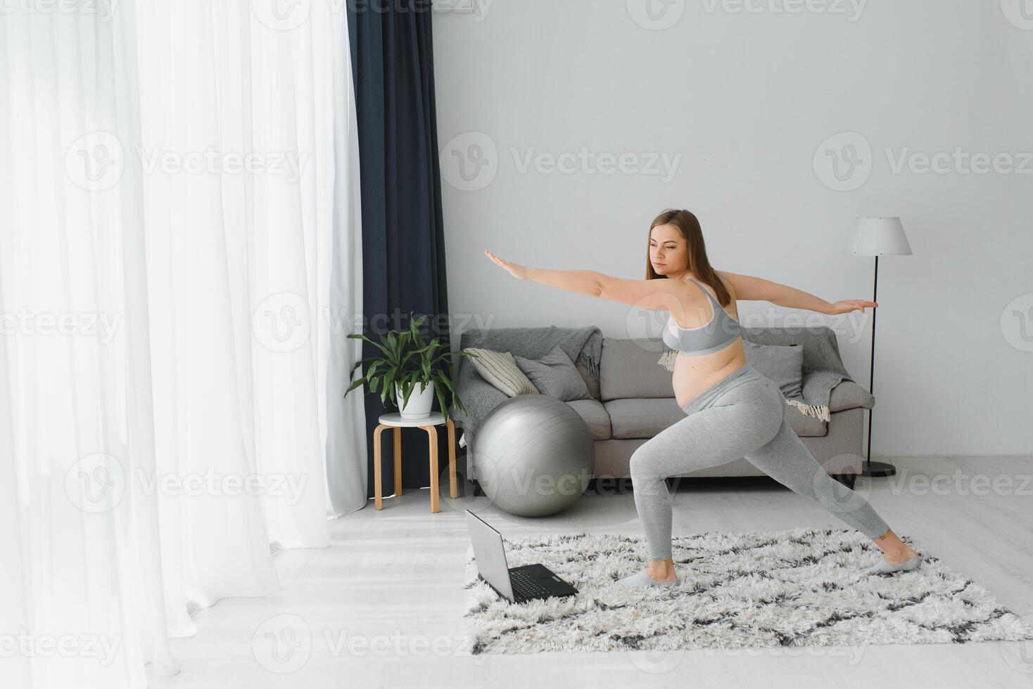 Beautiful young pregnant woman with laptop training at home photo