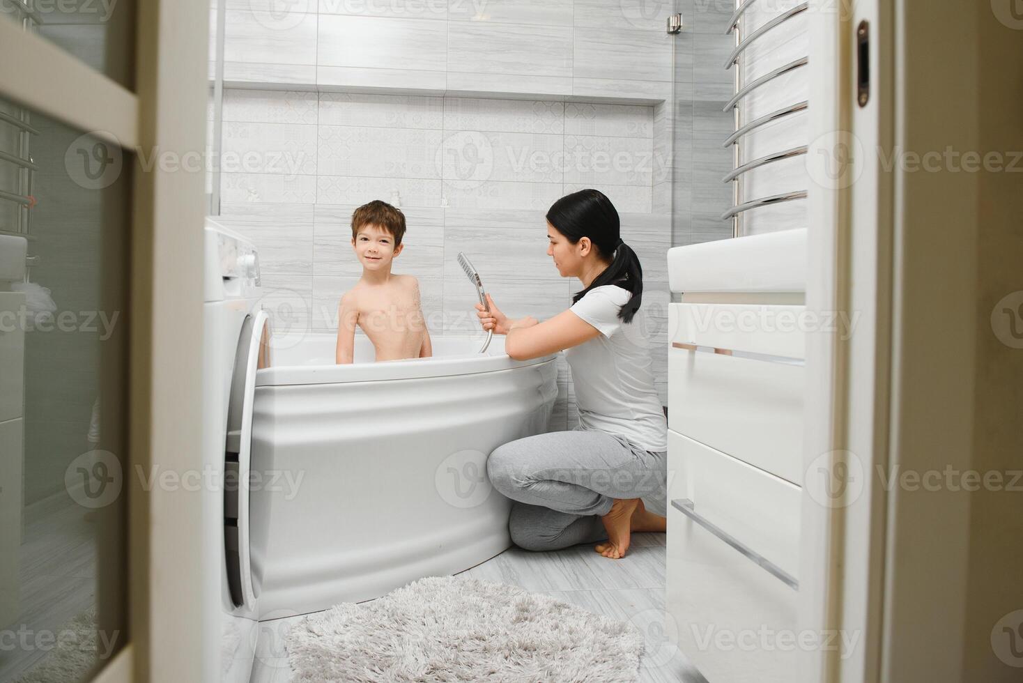 Mother washing little son in bathroom photo