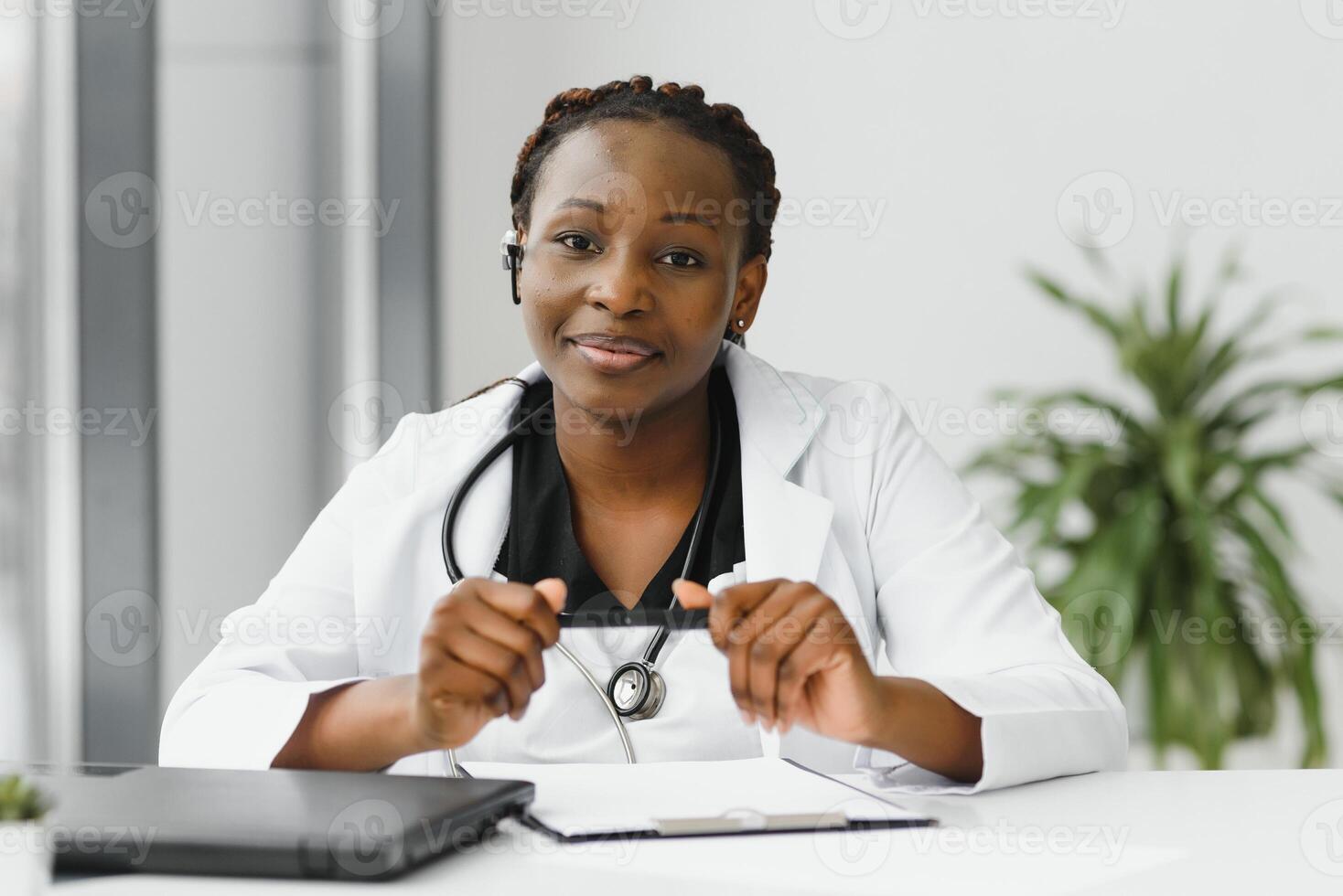 Closeup portrait of friendly, smiling confident female healthcare professional with lab coat, stethoscope, arms crossed. Isolated hospital clinic background. Time for an office visit. photo