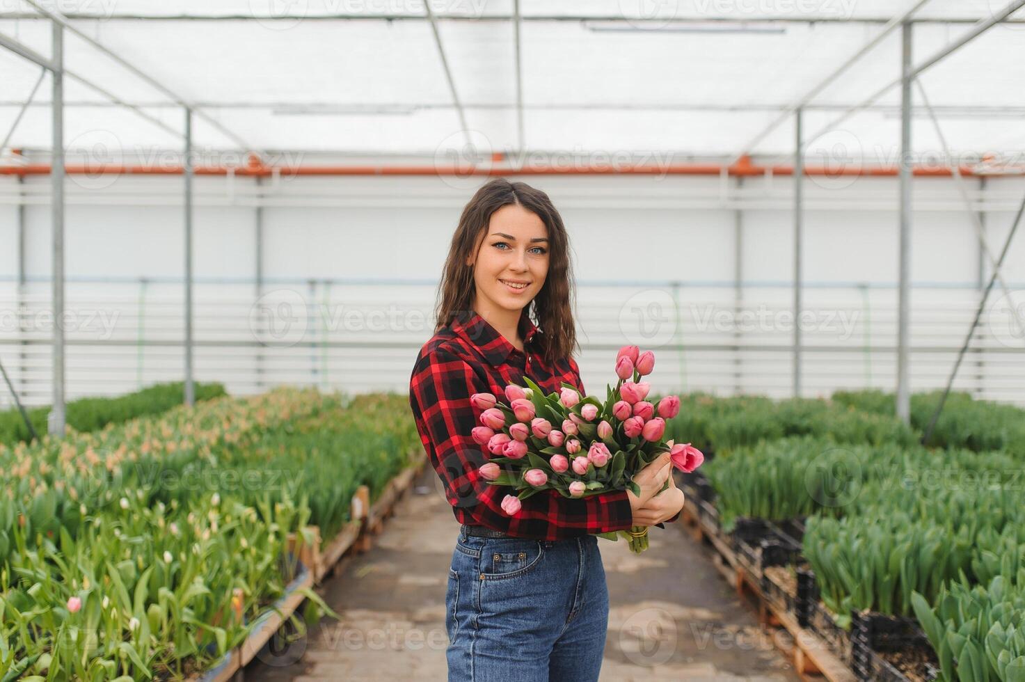 Beautiful young smiling girl, worker with flowers in greenhouse. Concept work in the greenhouse, flowers. photo