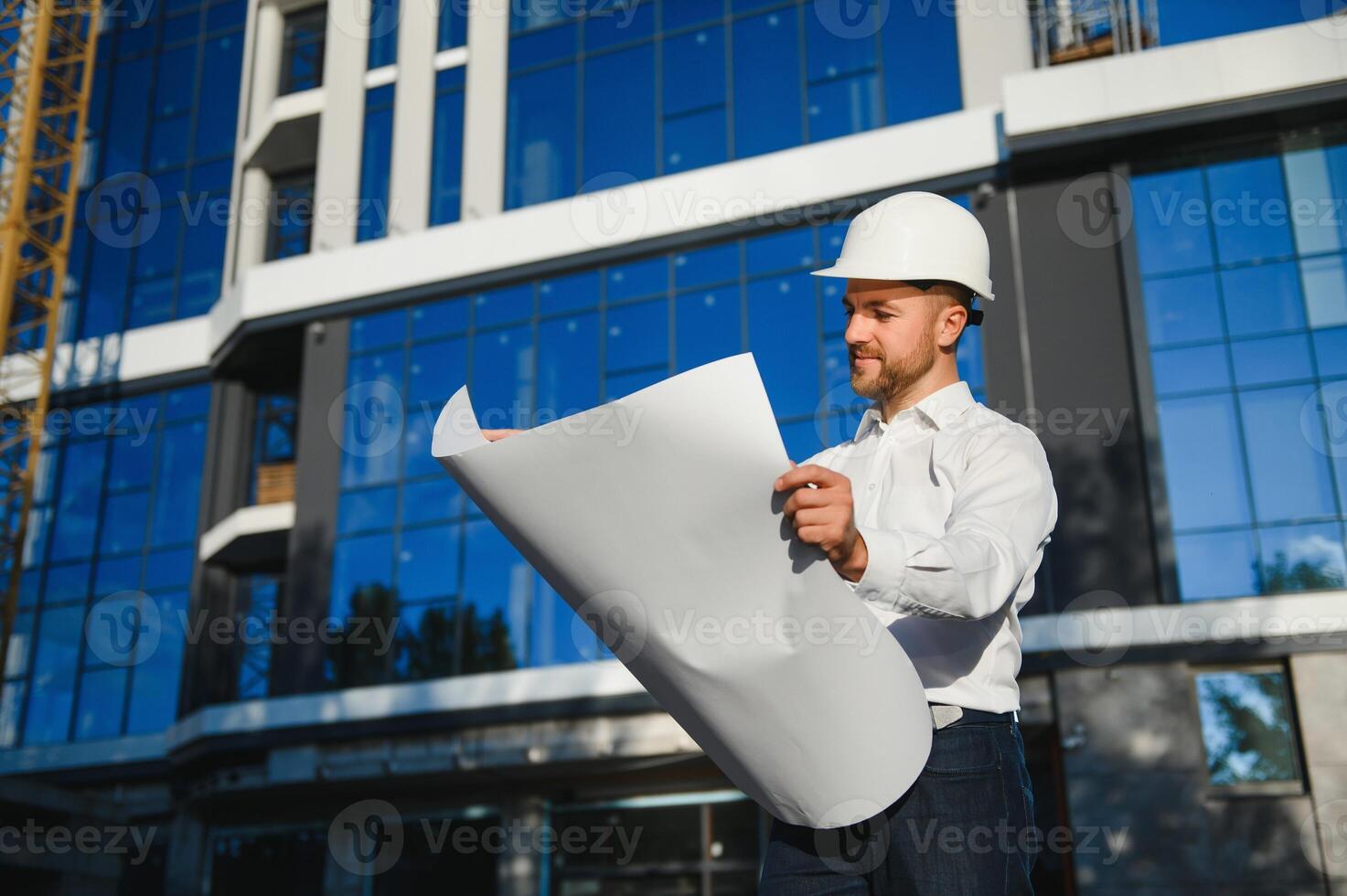 Engineer next to building cranes. Concept - large construction project. Architect directs the construction process. Drawings and tablet in the hands. photo