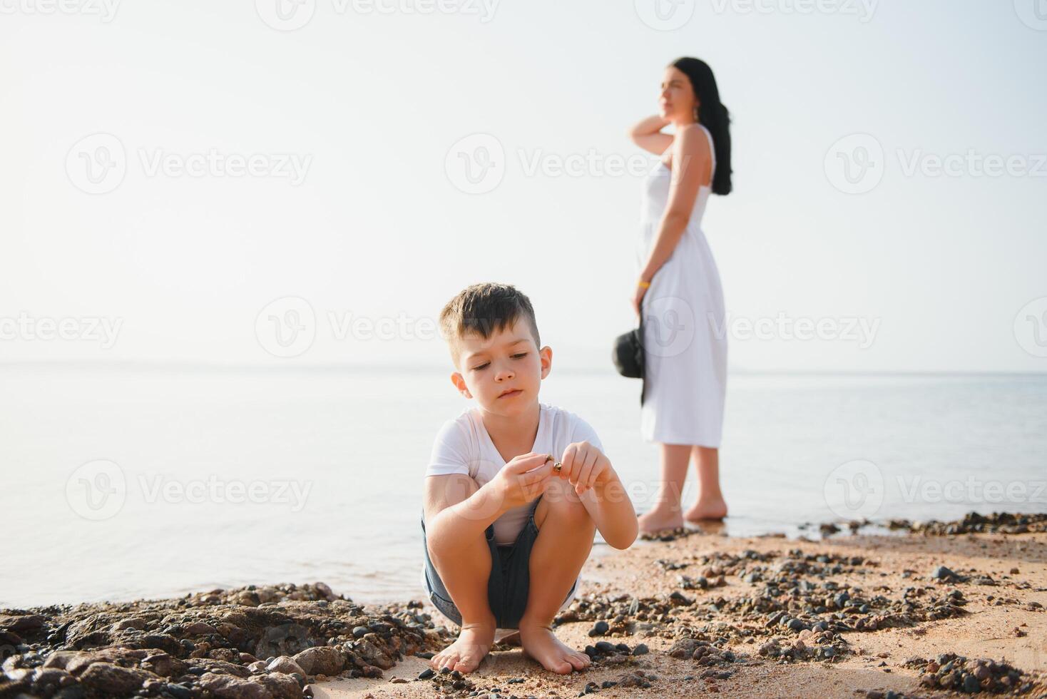 Happy mother and son walk along the ocean beach having great family time on vacation on Pandawa Beach, Bali. Paradise, travel, vacation concept photo