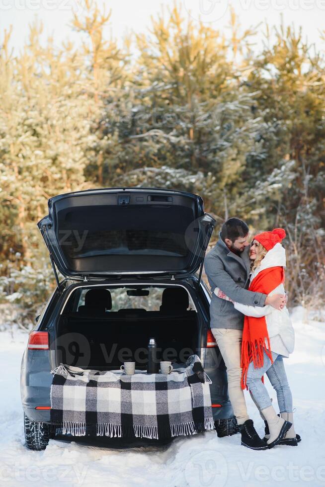 Winter picnic in the forest. Love story in snow. couple in winter play in snow and hugging near the pine. Two lovers on winter walk. Valentine's Day for couple in rustic style. Winter lovestory photo