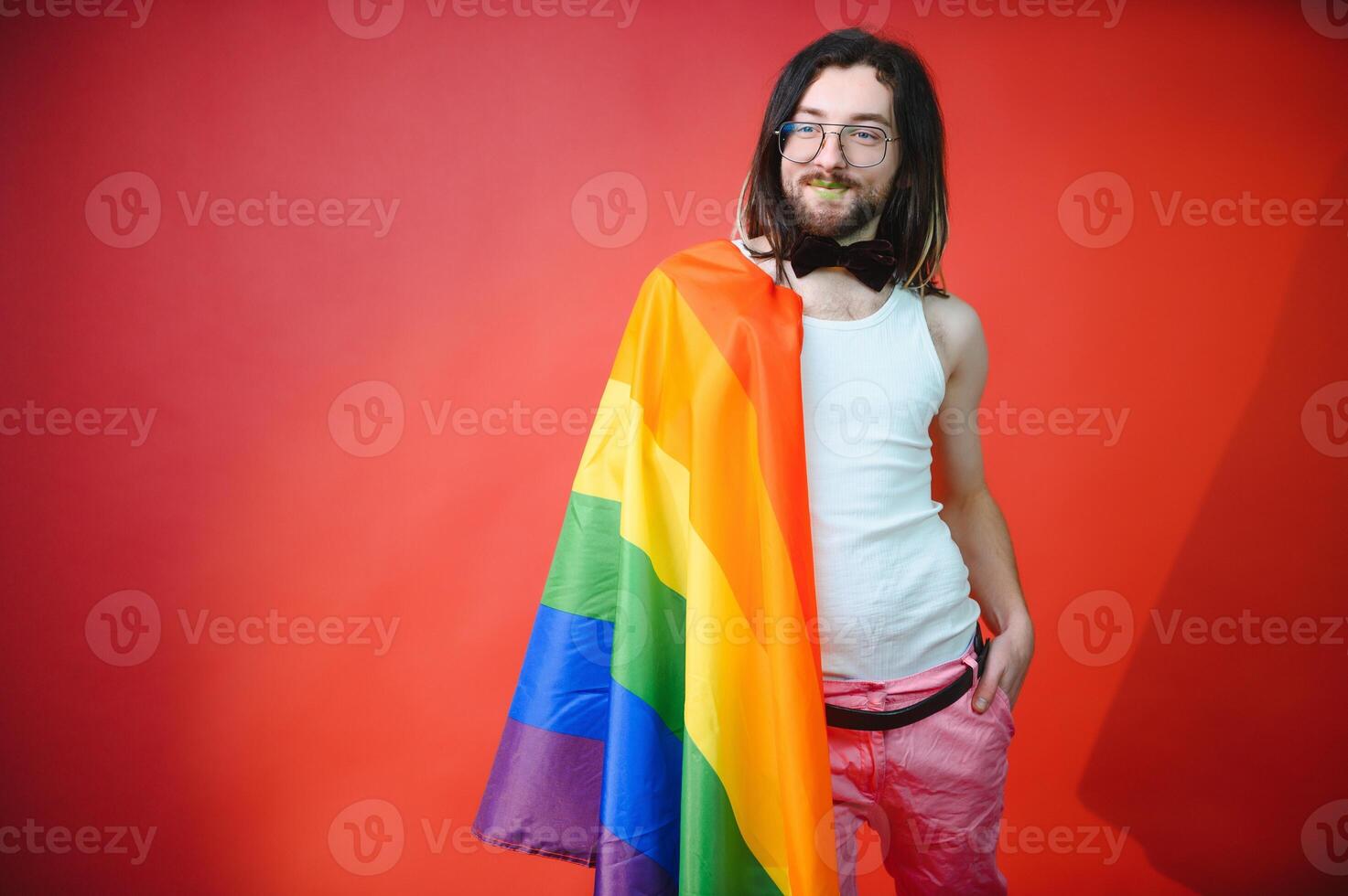 hermoso joven hombre con orgullo movimiento lgbt arco iris bandera en hombro en contra blanco antecedentes. hombre con un gay orgullo bandera. foto