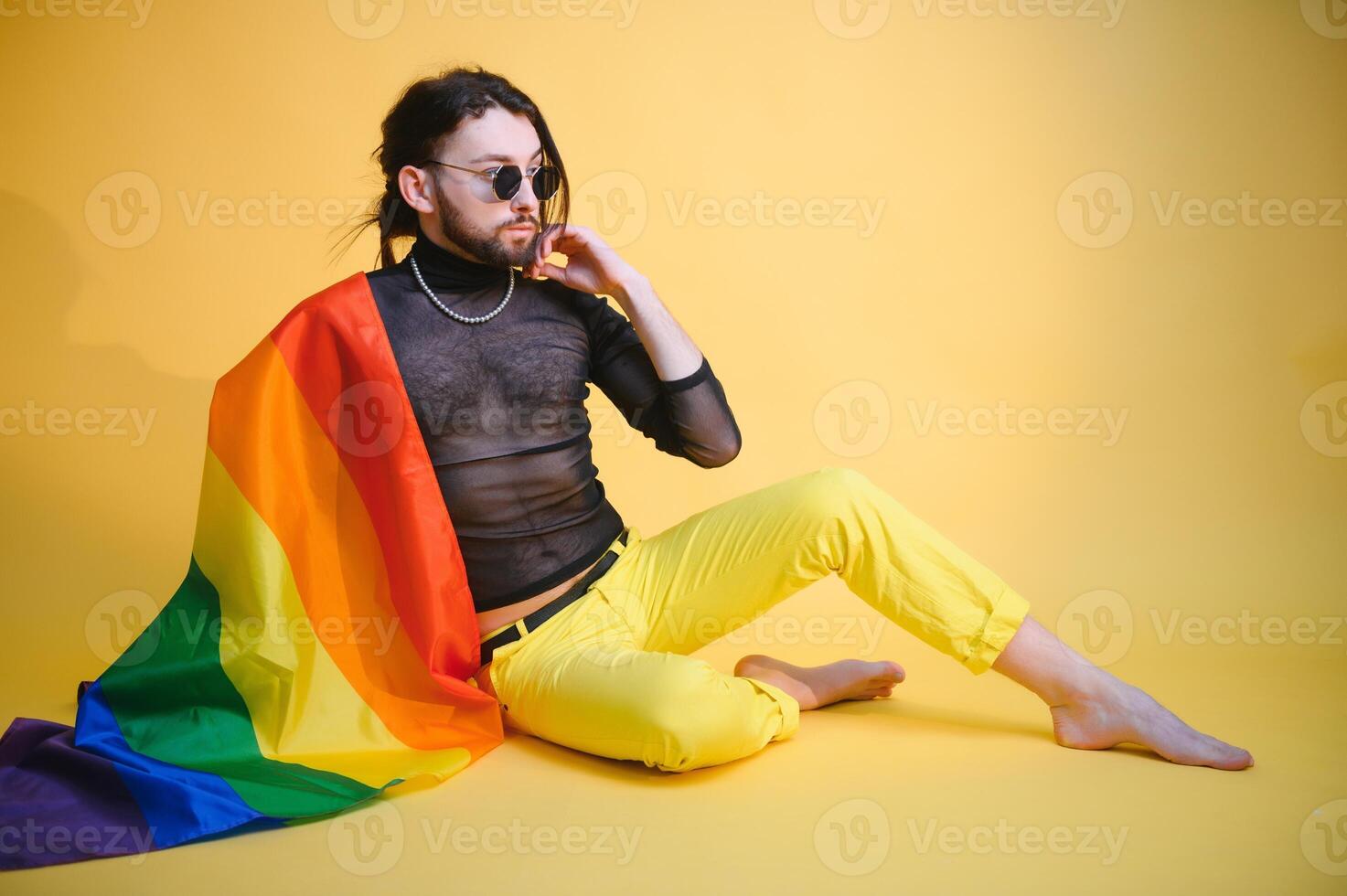 hermoso joven hombre con orgullo movimiento lgbt arco iris bandera en hombro en contra blanco antecedentes. hombre con un gay orgullo bandera. foto