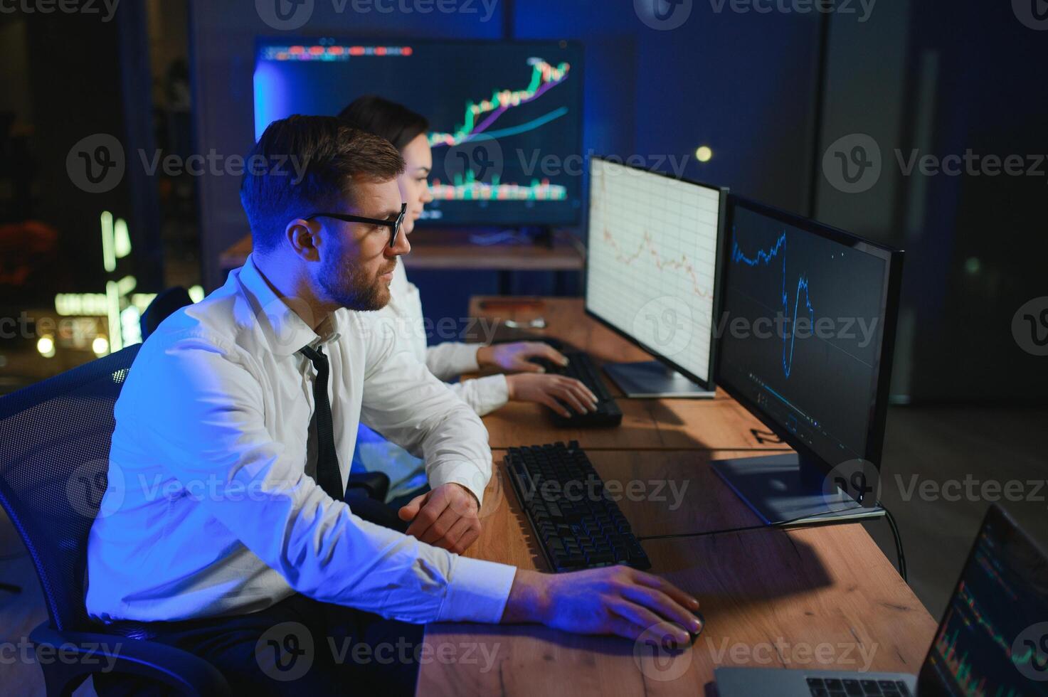 Team of stockbrokers are having a conversation in a dark office with display screens photo
