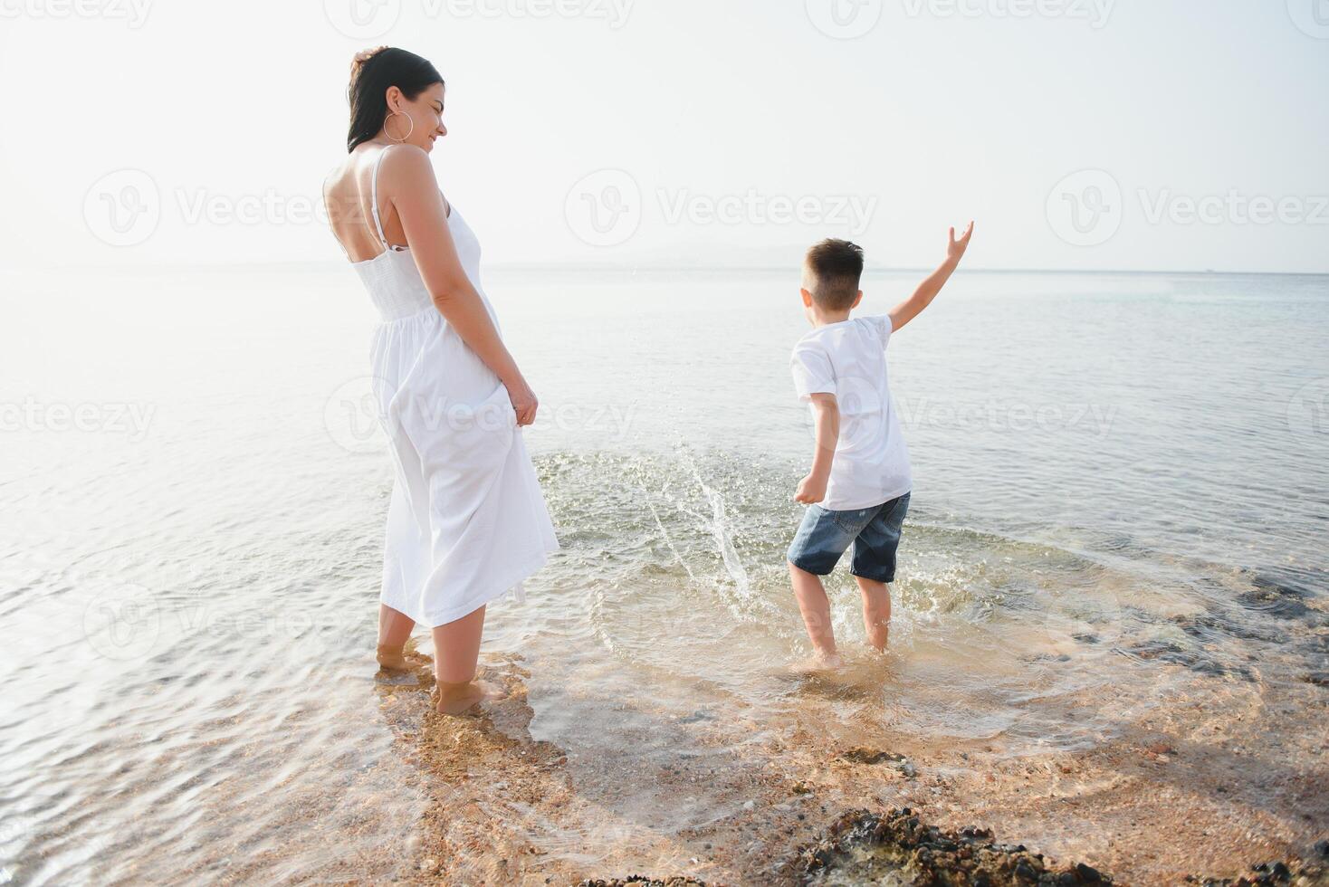 Happy mother and son walk along the ocean beach having great family time on vacation on Pandawa Beach, Bali. Paradise, travel, vacation concept photo