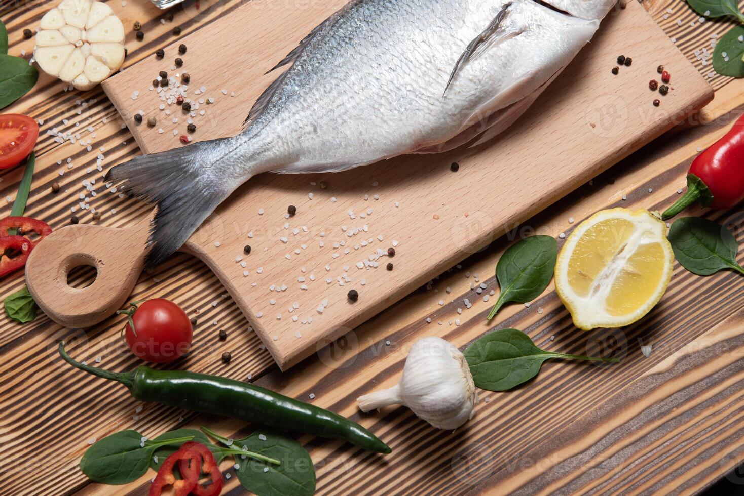 Pescado dorado crudo con especias para cocinar en la tabla de cortar. dorado de pescado fresco foto