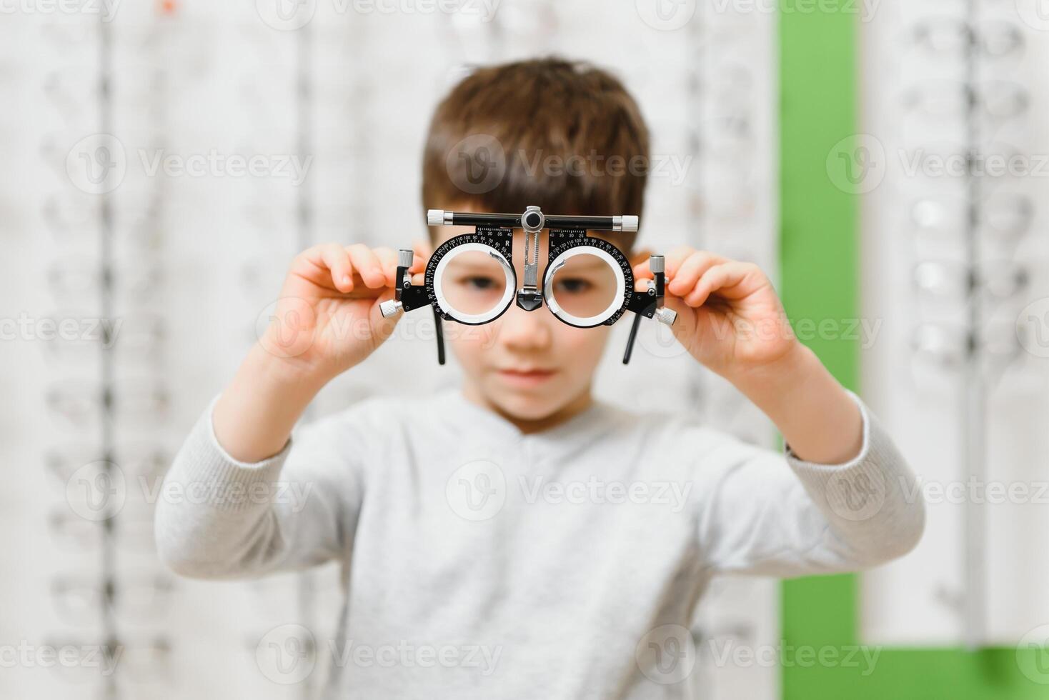 child boy showing trial frame in ophthalmology clinic, selective focus. photo