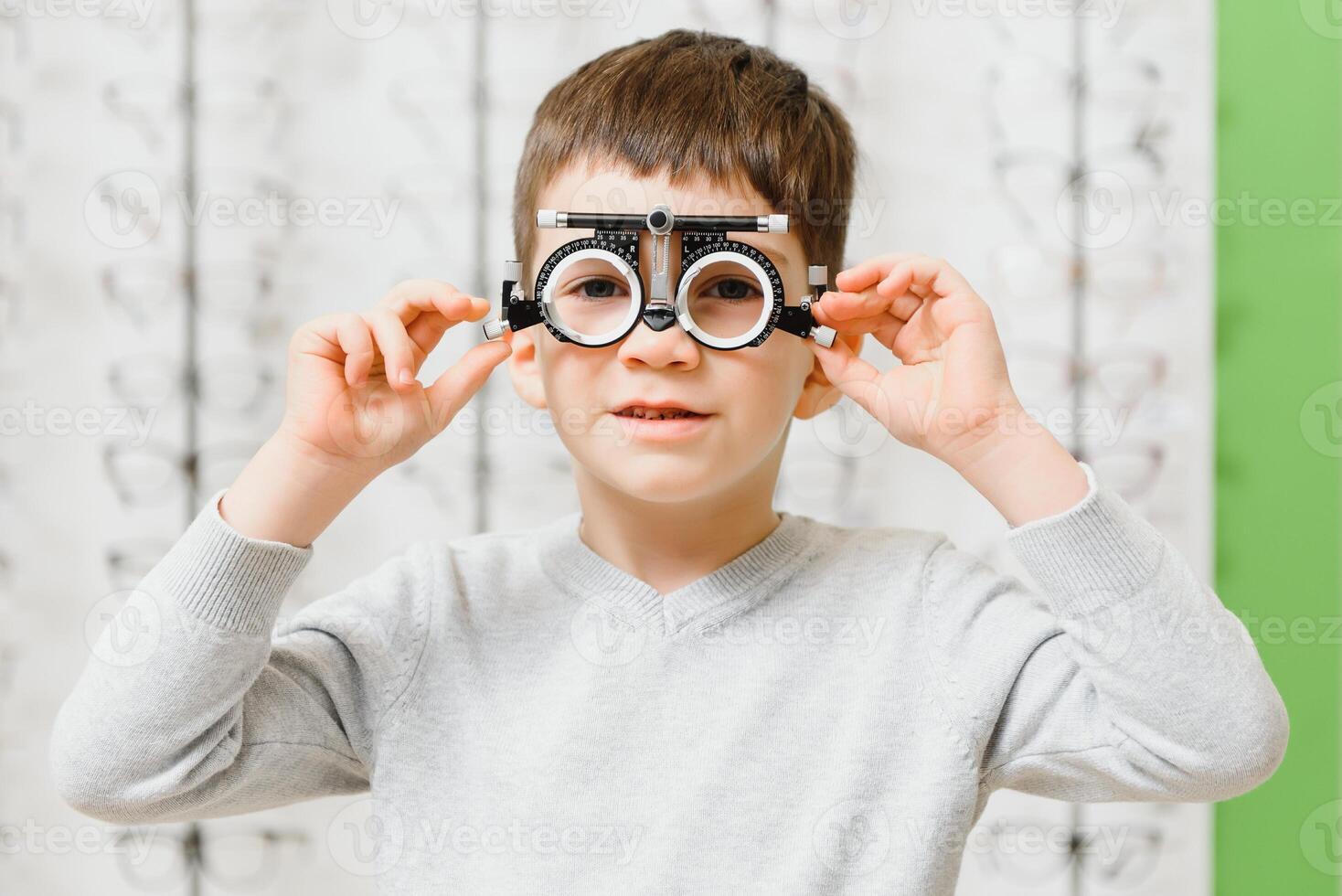 Boy put trial frame at clinic Medical Optician concept photo