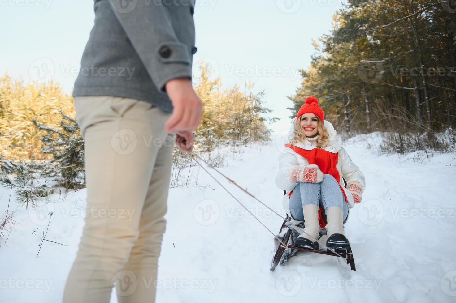Beautiful young couple in love having fun on a winter vacation in mountains, boyfriend pushing girlfriend on a sled, enjoying snowy, foggy winter day outdoor photo
