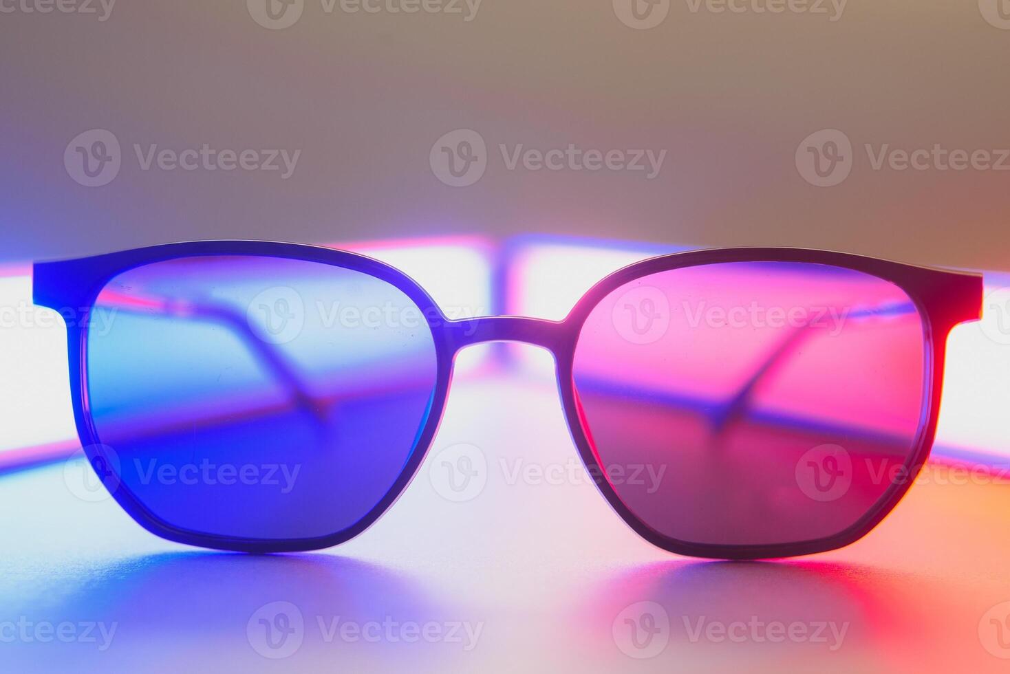 Stylish sunglasses shot using pink and blue abstract colored lighting with copy space. photo