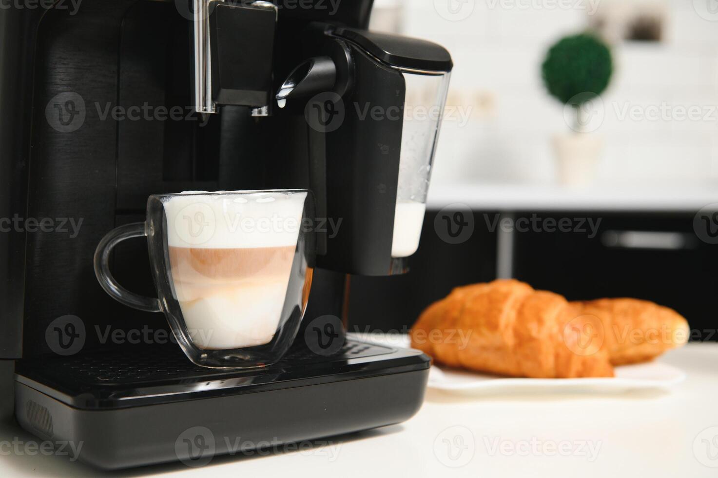 Modern coffee machine with glass cup of latte on white marble countertop in kitchen photo