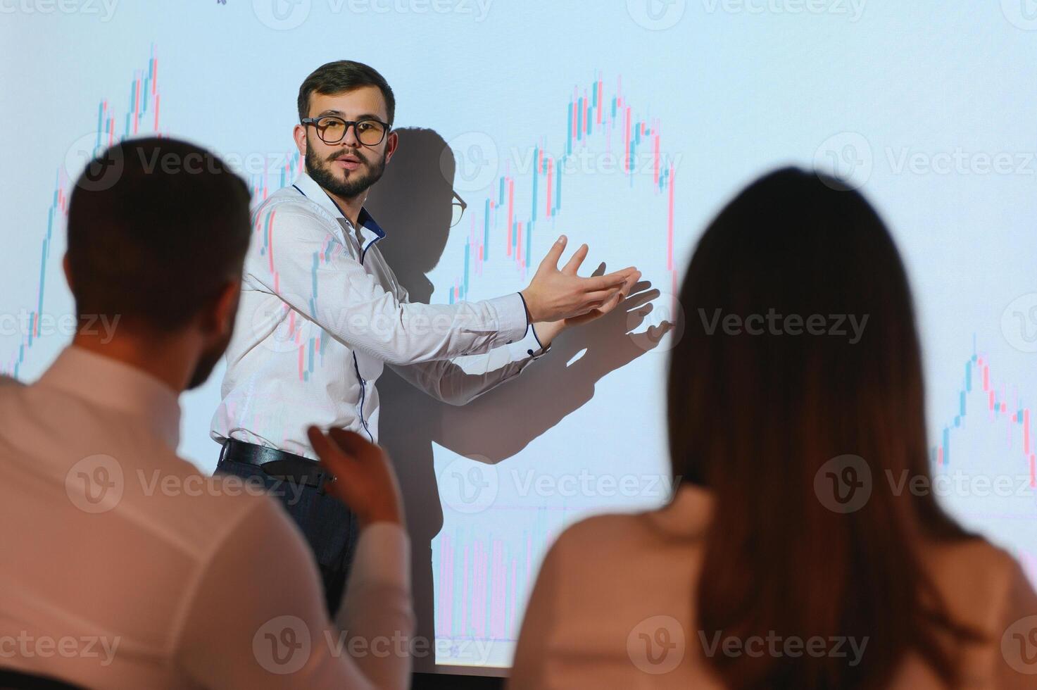 Trading teaching. Male leader talking to employees, showing the plan on the projector in office of stock exchange company. photo