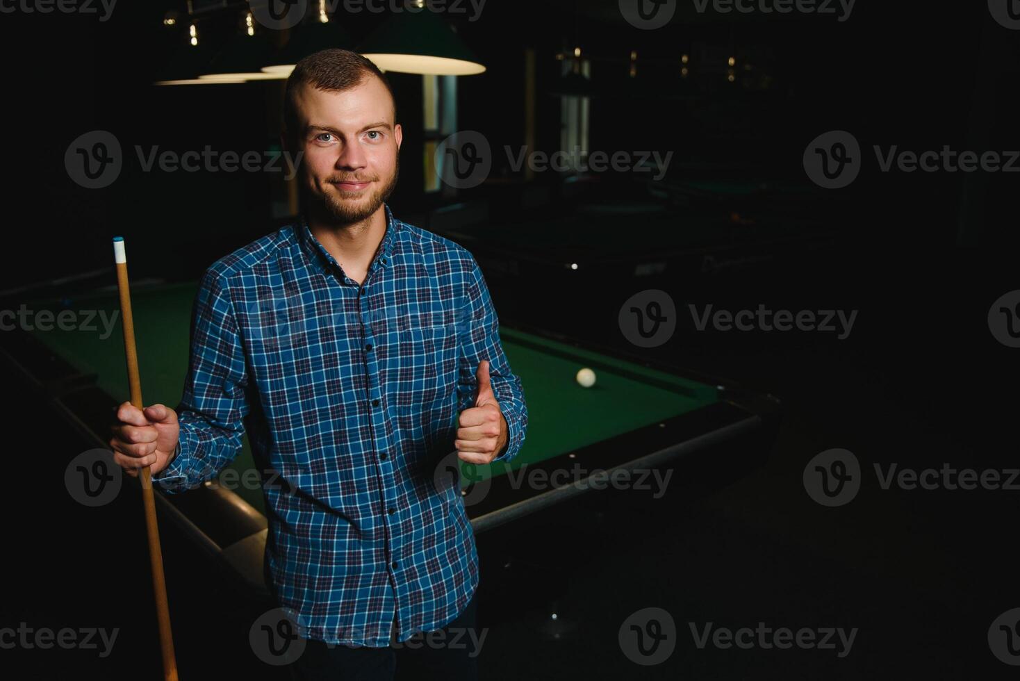 Young man playing billiards in the dark billiard club photo