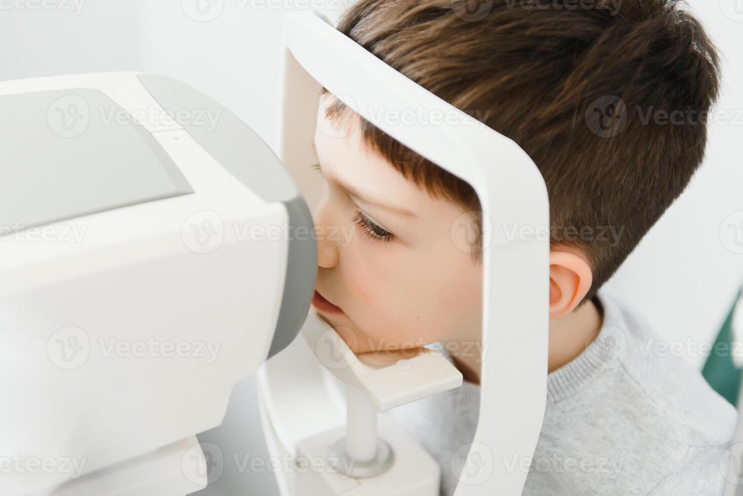 Optometry concept. Female optometrist optician doctor examines eyesight of child boy in eye ophthalmological clinic. photo