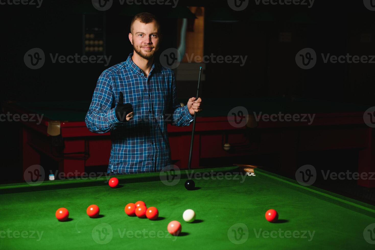 Young man playing billiards in the dark billiard club photo