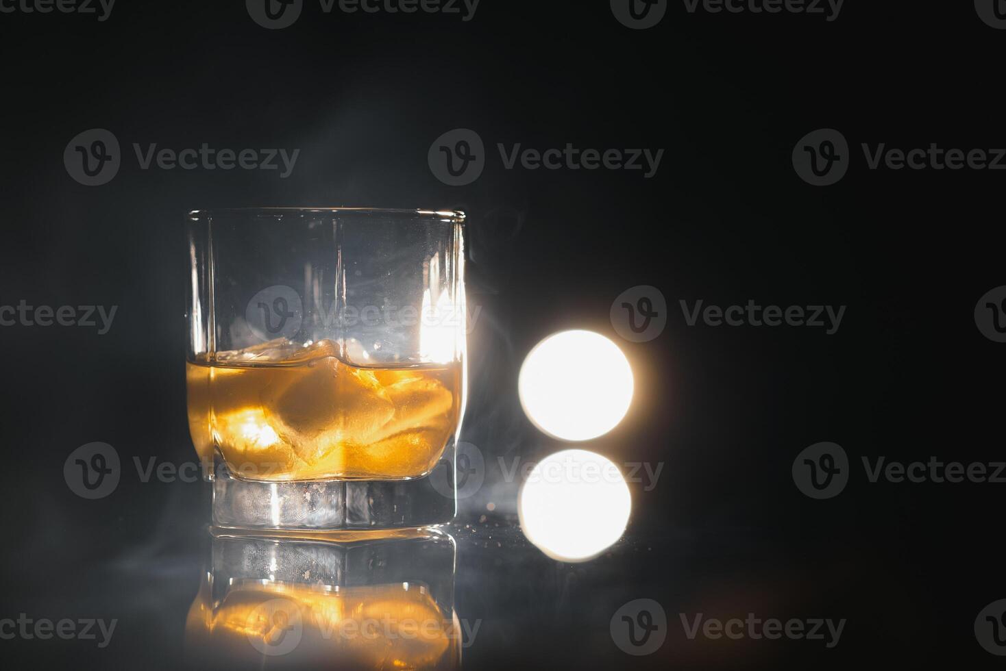 whiskey with ice on black background with smoke photo