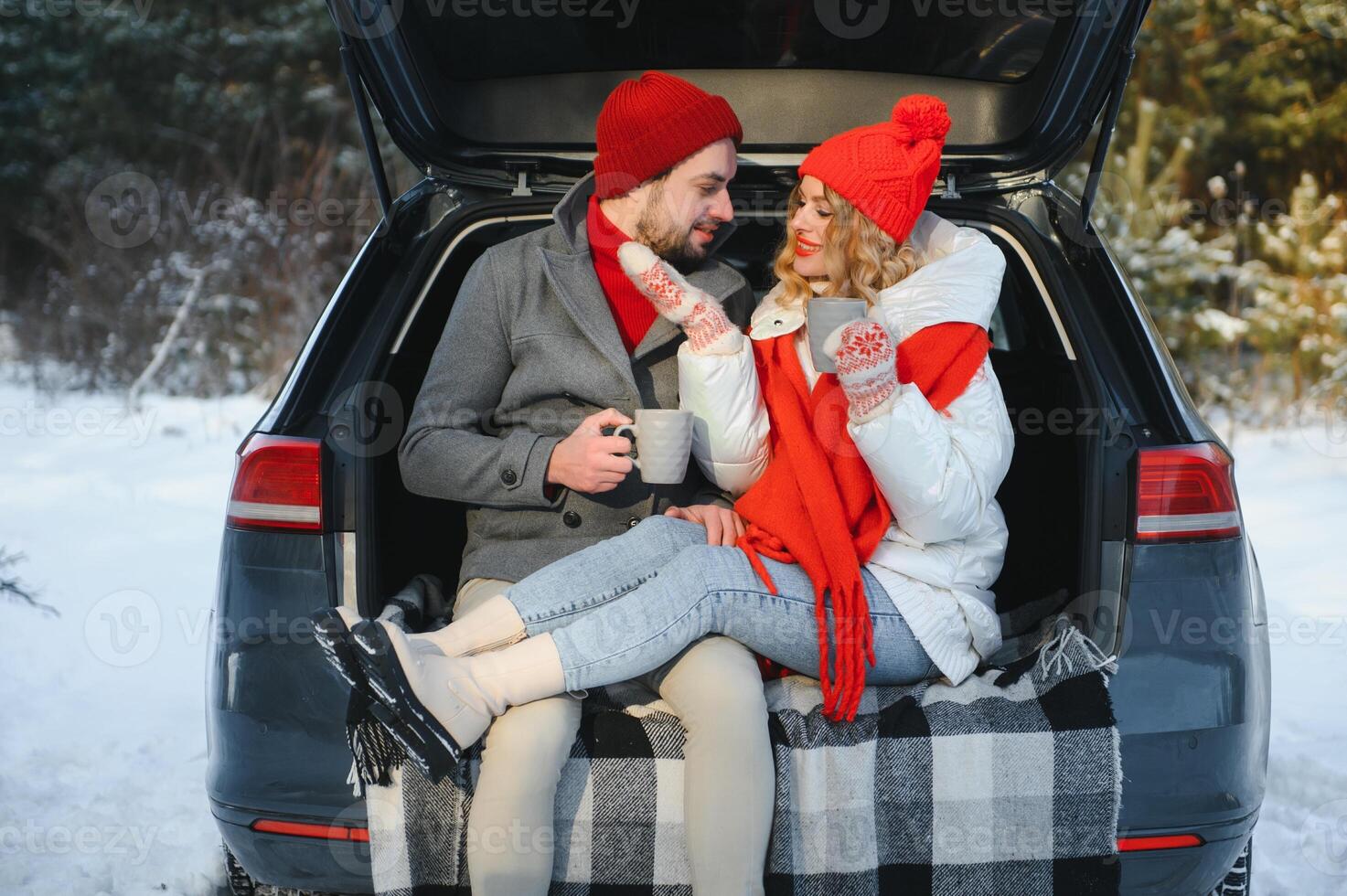 Happy couple sitting in open car back, having stop off. Romantic traveling concept. Winter forest. photo