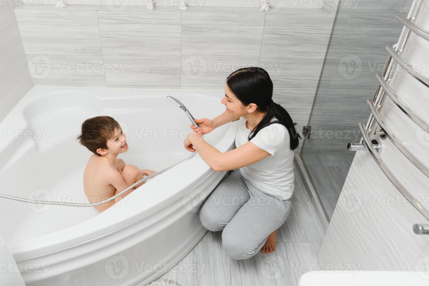 Mother washing little son in bathroom photo