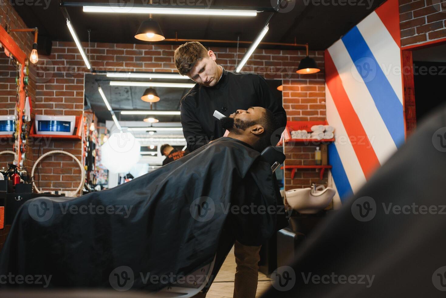 visitando peluquería. africano americano hombre en un elegante Barbero tienda foto