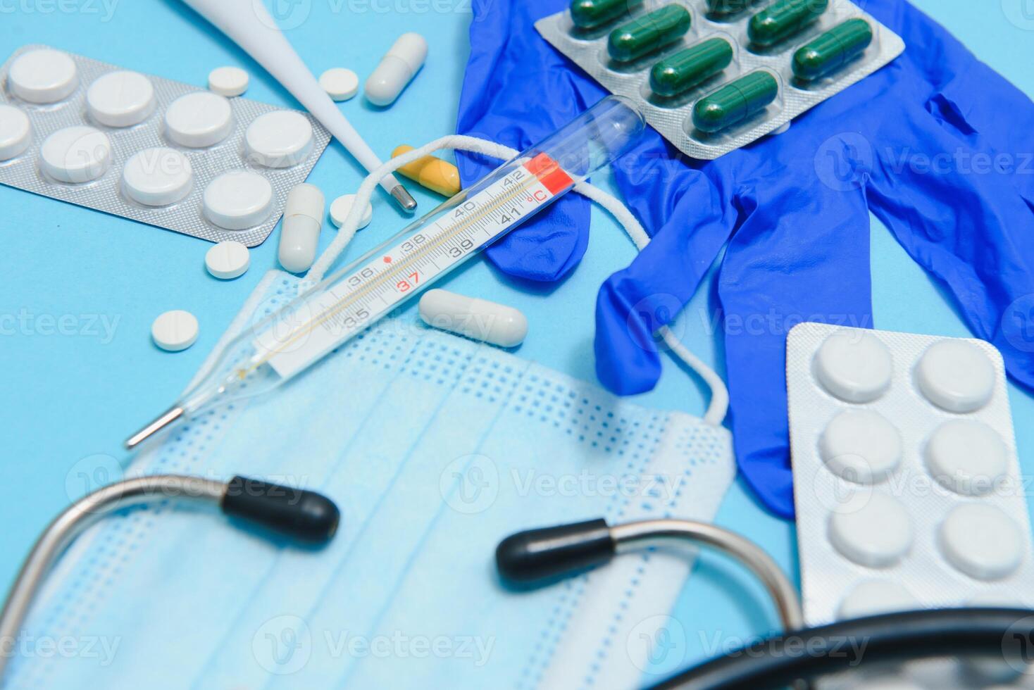 Top view of medicines, work tools and accessories doctor, nurse. Medical set - Tablets, thermometer, syringe, ampoules, adhesive plaster and statoscope on a blue background. Flat lay. photo