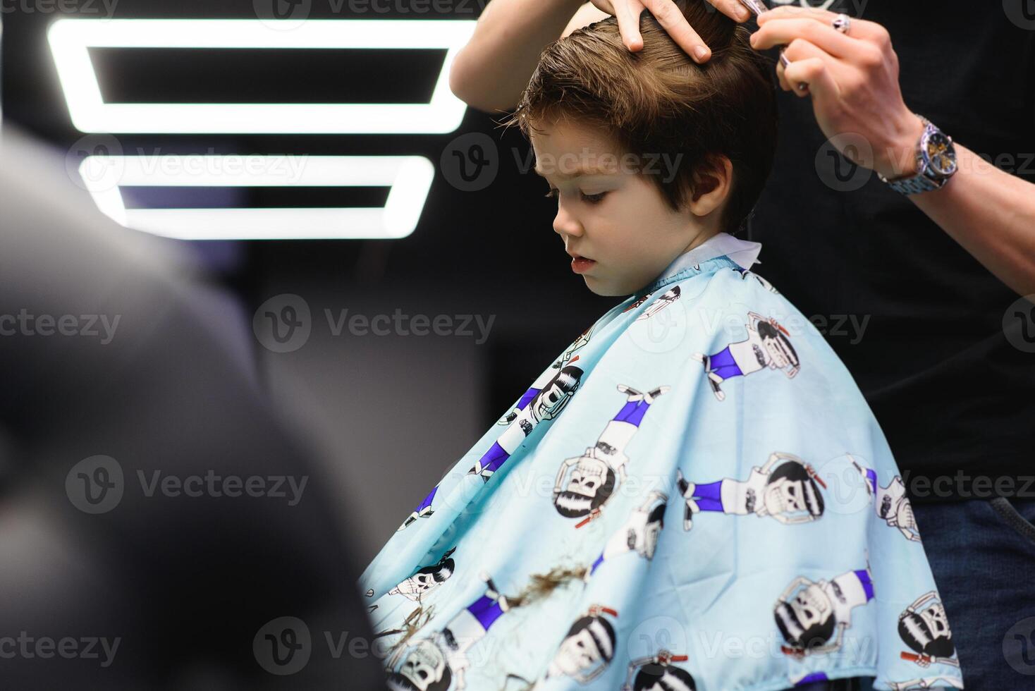 Cheerful Caucasian boy getting hairstyle in barbershop photo