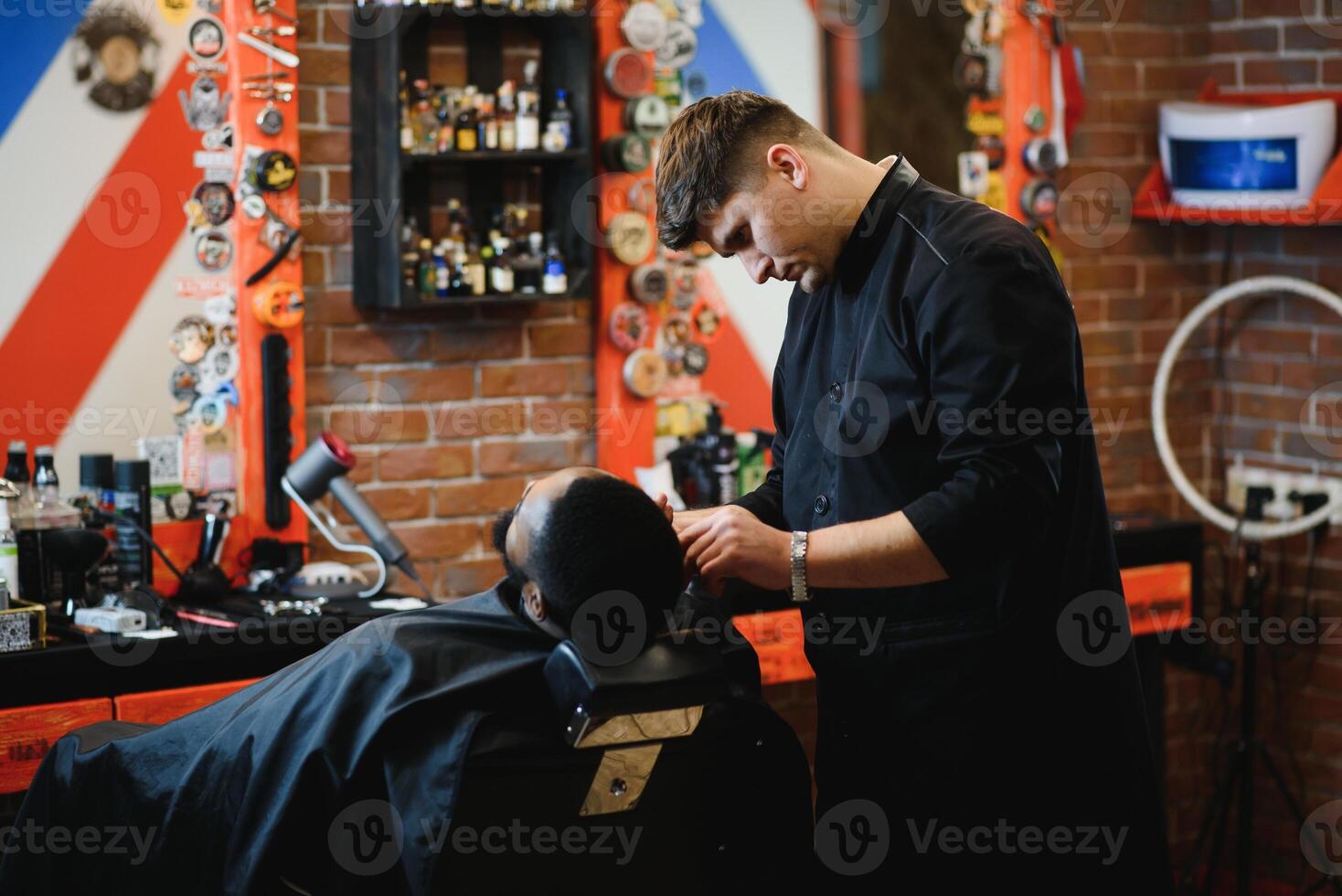 African male client getting haircut at barber shop from professional hairstylist. photo