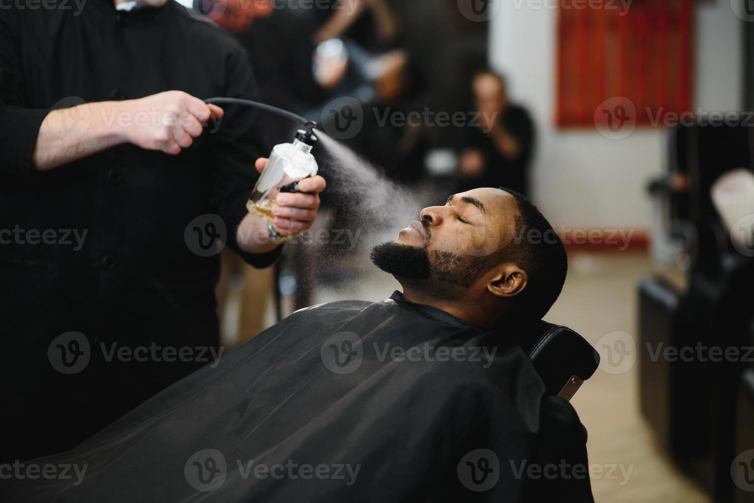 africano masculino cliente consiguiendo Corte de pelo a Barbero tienda desde profesional estilista. foto