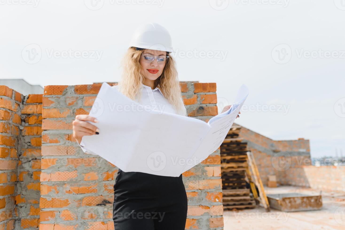 construcción ingeniero. niña con construcción documentación. un mujer en un blanco difícil sombrero en contra el techo de un edificio. construcción de un nuevo casa foto