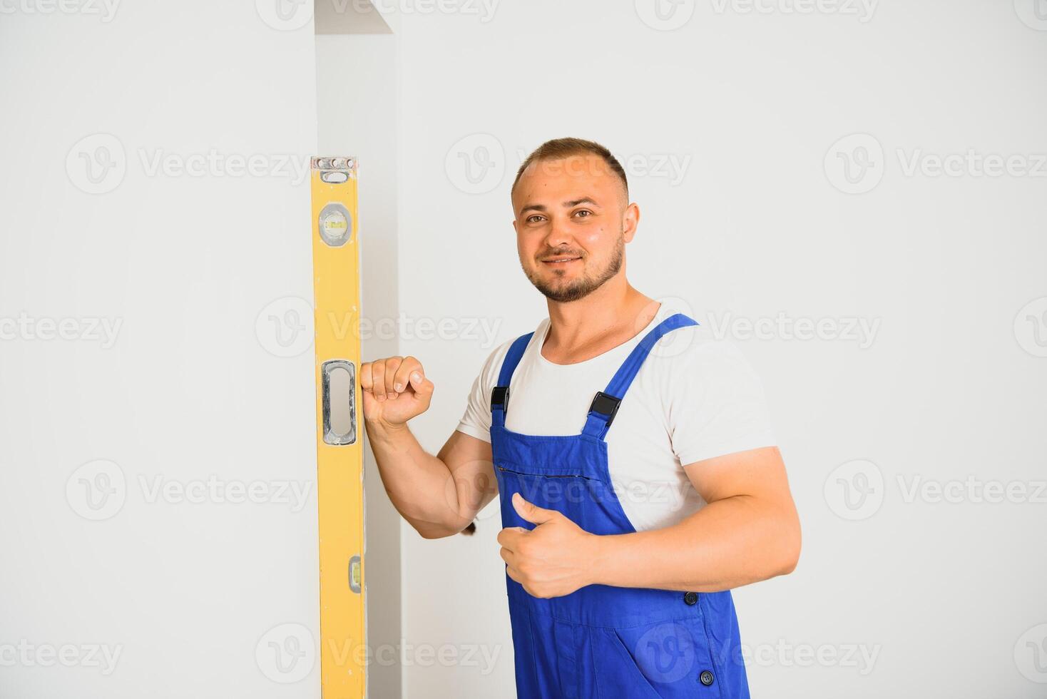 Portrait of young specialist making wall plane in new building photo