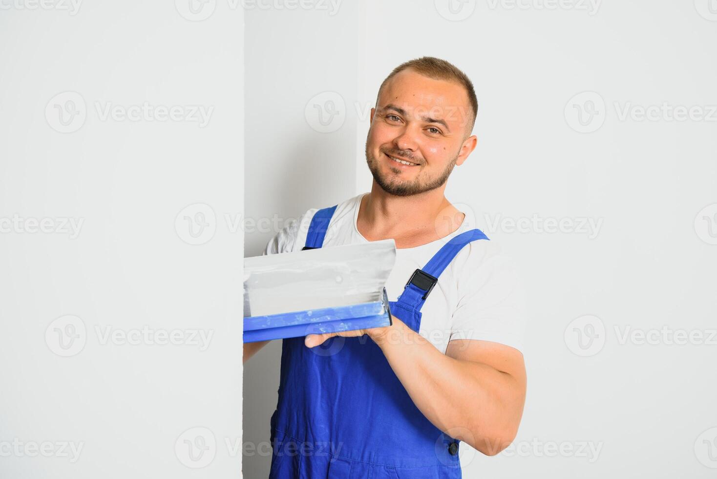 A man in overalls uses a trowel to cover the wall with cement photo