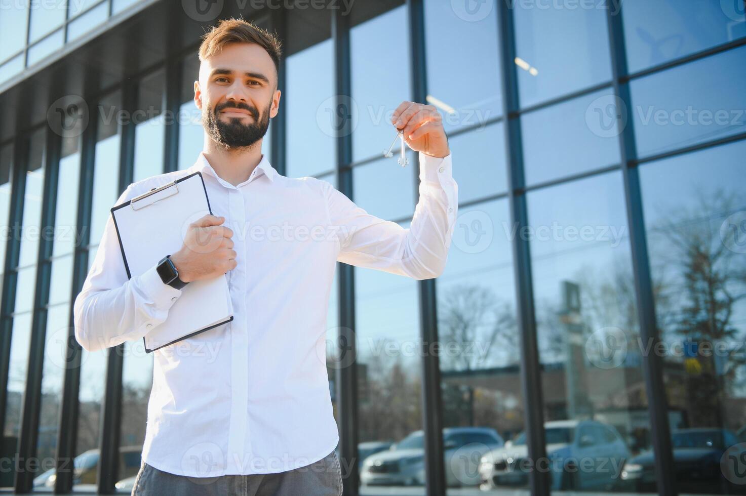 Real estate agent holding key on blurred background, closeup photo