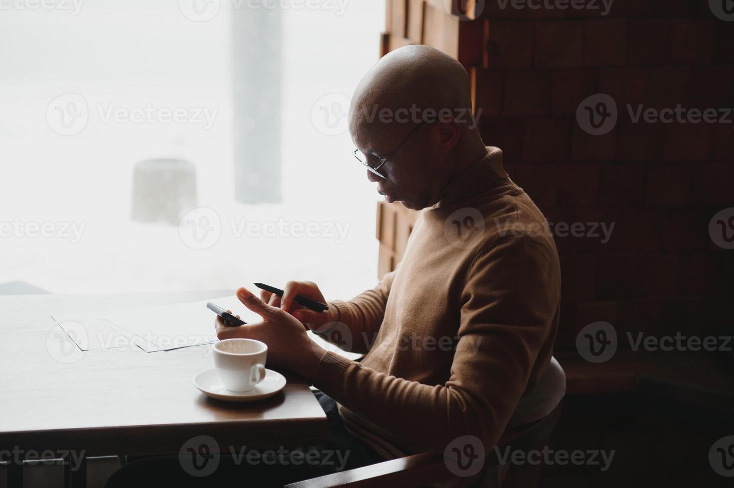 Knowledge, learning, education and technology. Casually dressed hardowrking A-student with Afro hairstyle solving mathematical problems, sitting at cafe table with textbooks and electronic device. photo