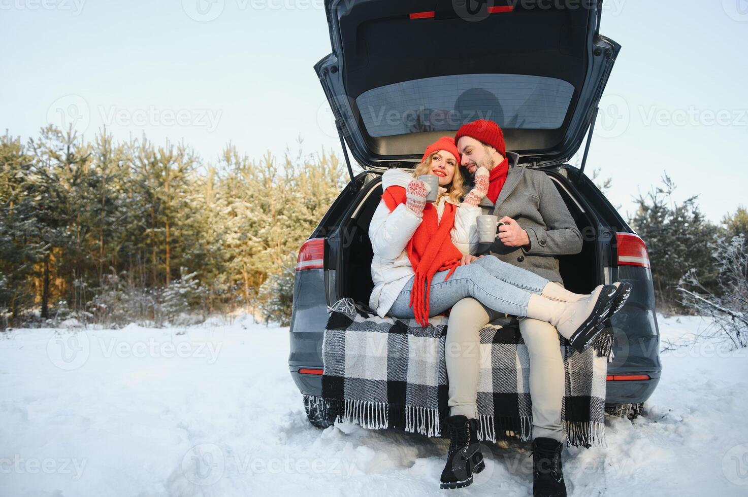 Happy couple sitting in open car back, having stop off. Romantic traveling concept. Winter forest. photo