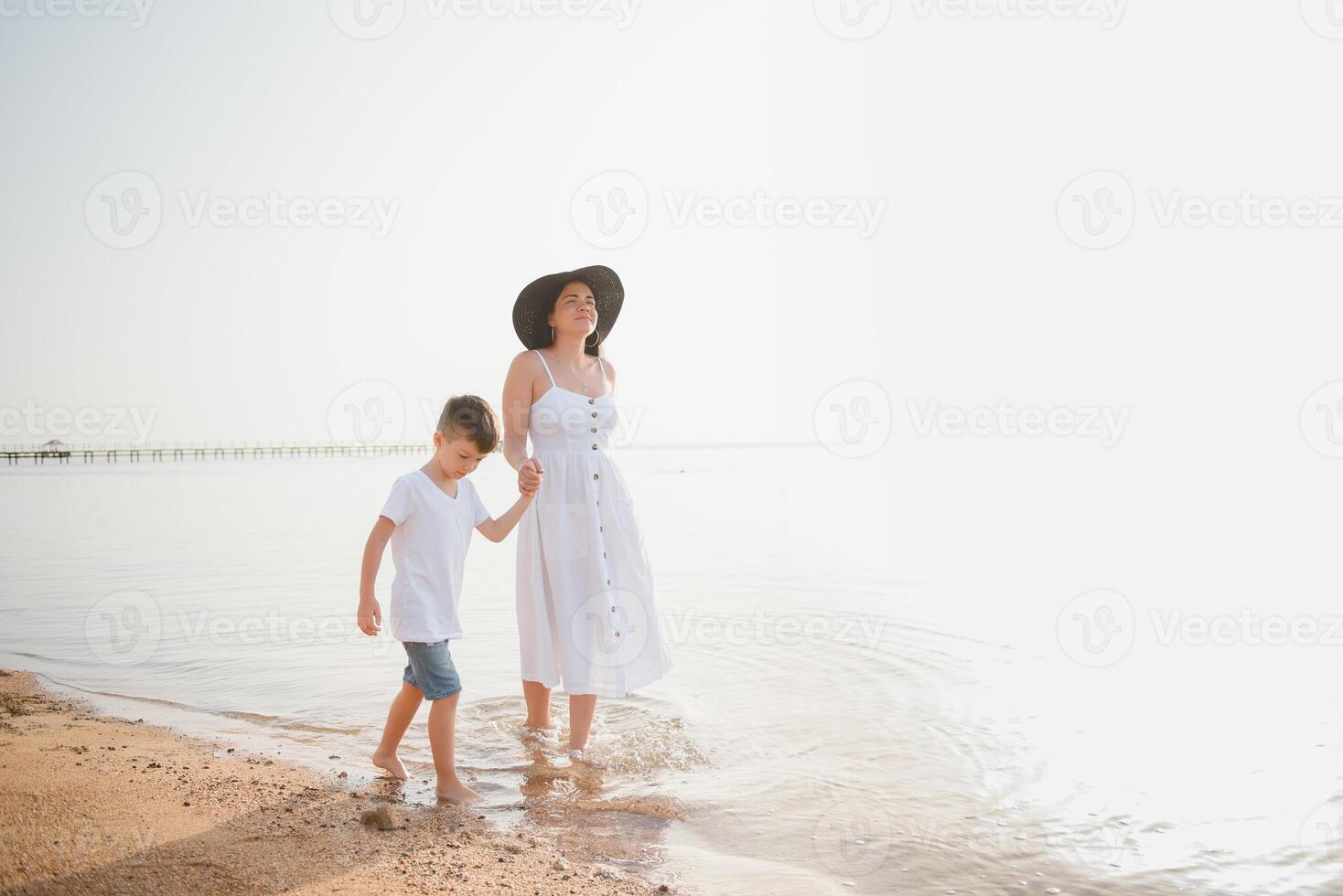 contento madre con hijo caminar en playa, familia a mar foto