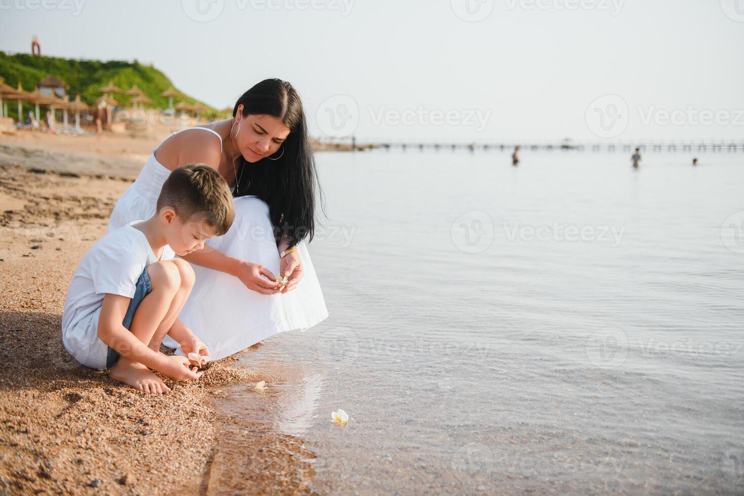 mother and son walking on sunset beach photo