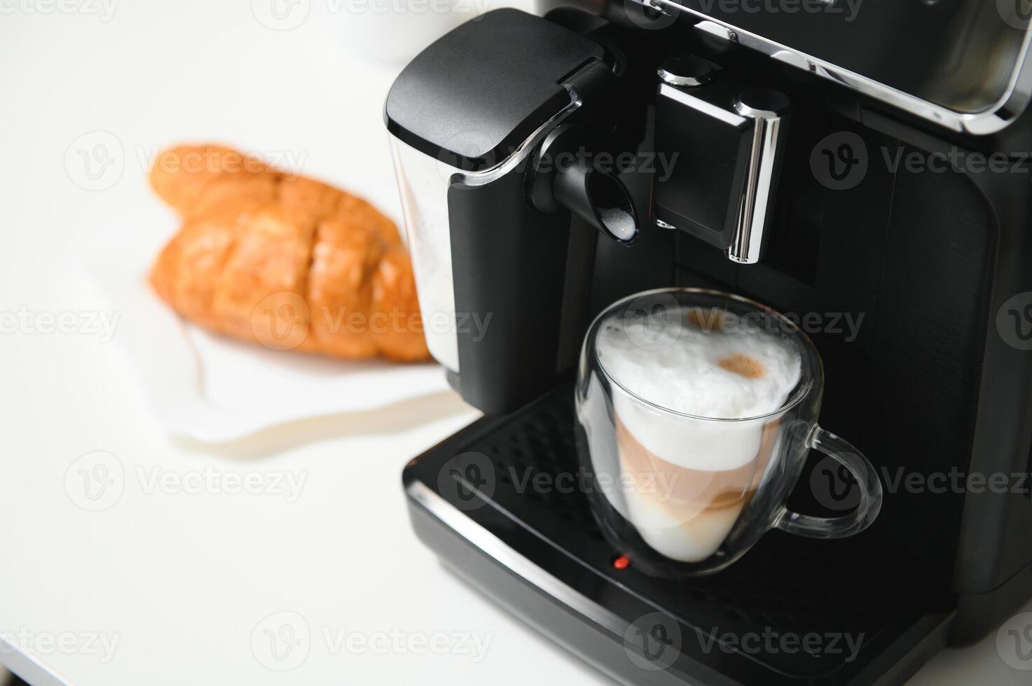 Modern coffee machine with glass cup of latte on white marble countertop in kitchen photo
